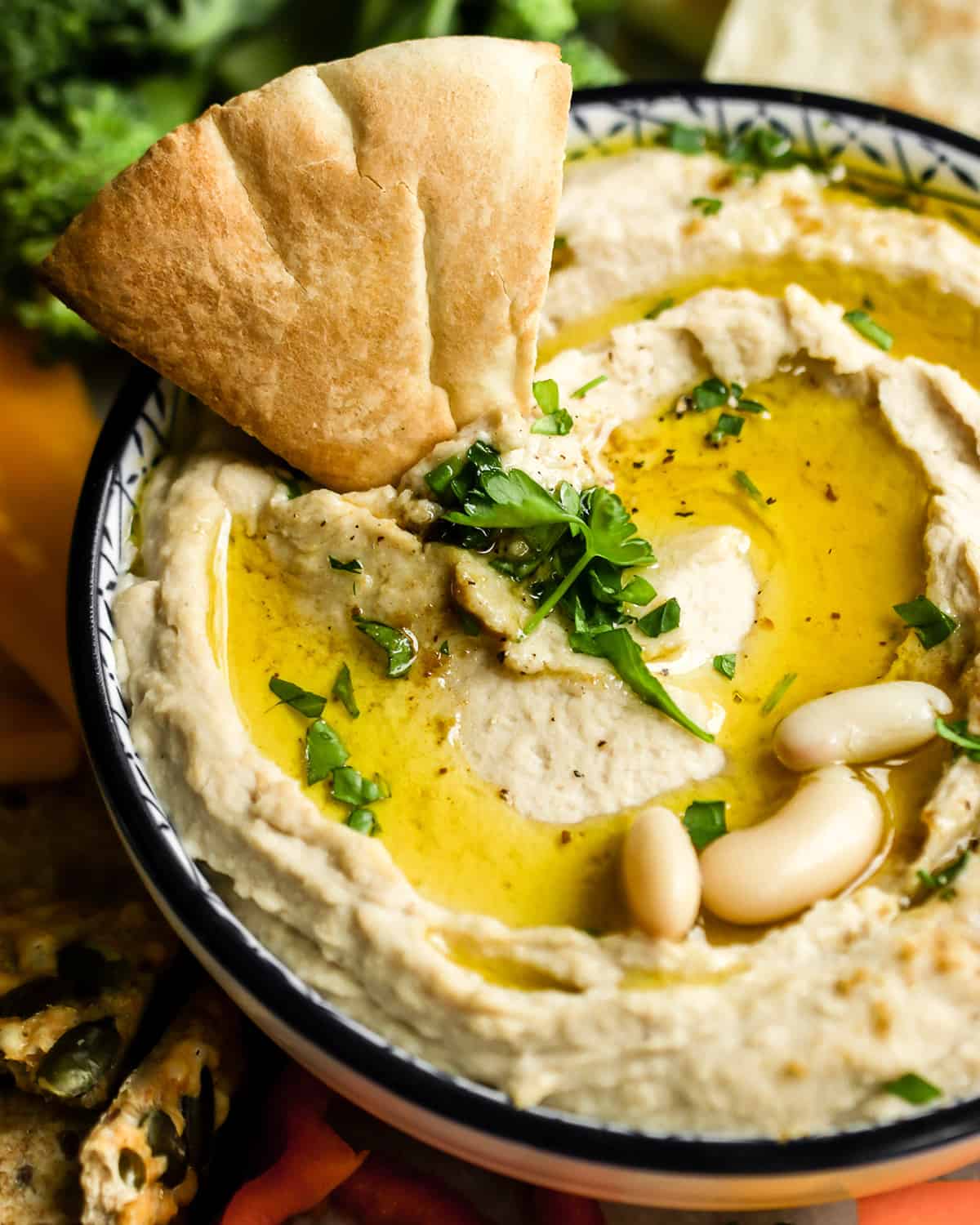 a piece of pita bread in a bowl of White Bean Hummus
