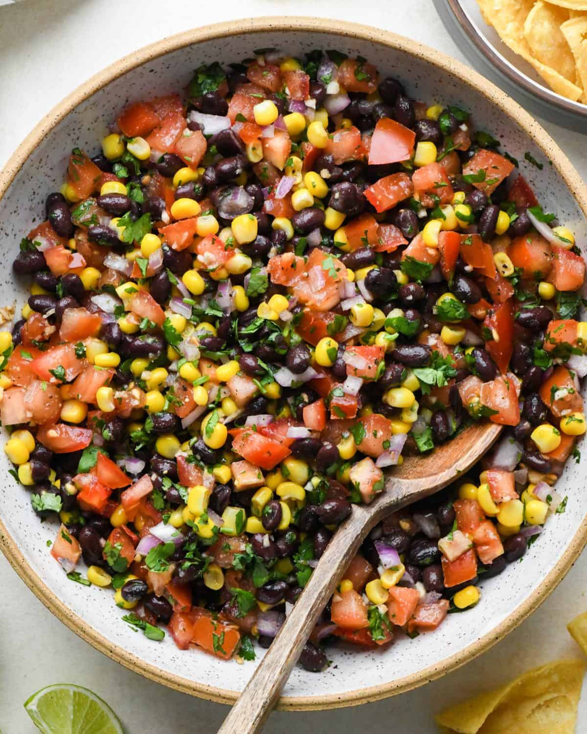 Black Bean Corn Salsa in a bowl with a wooden spoon