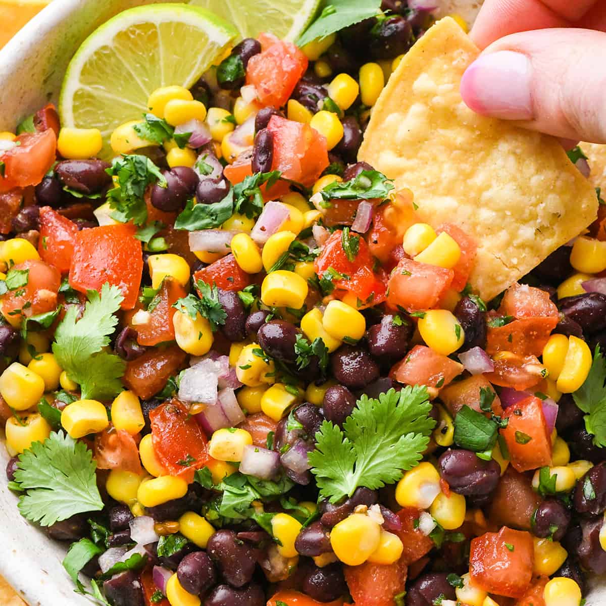 a chip being dipped into a bowl of Black Bean Corn Salsa