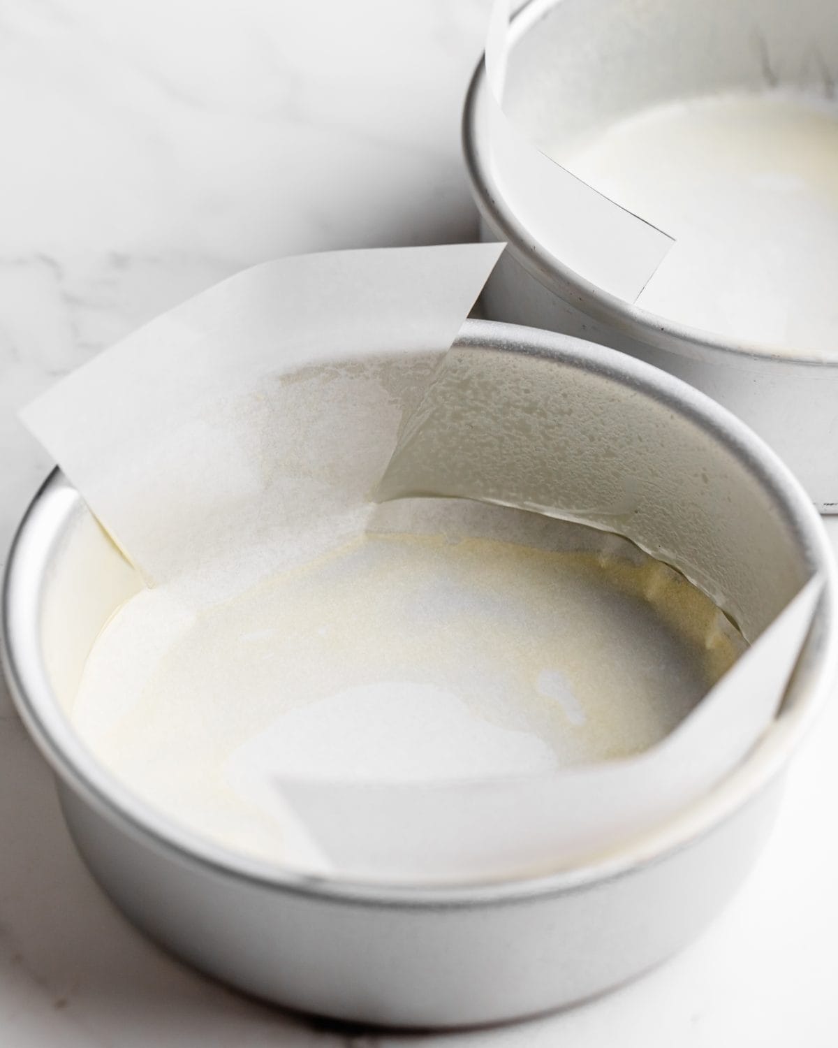 making chocolate cake recipe - two cake pans line with parchment paper and greased