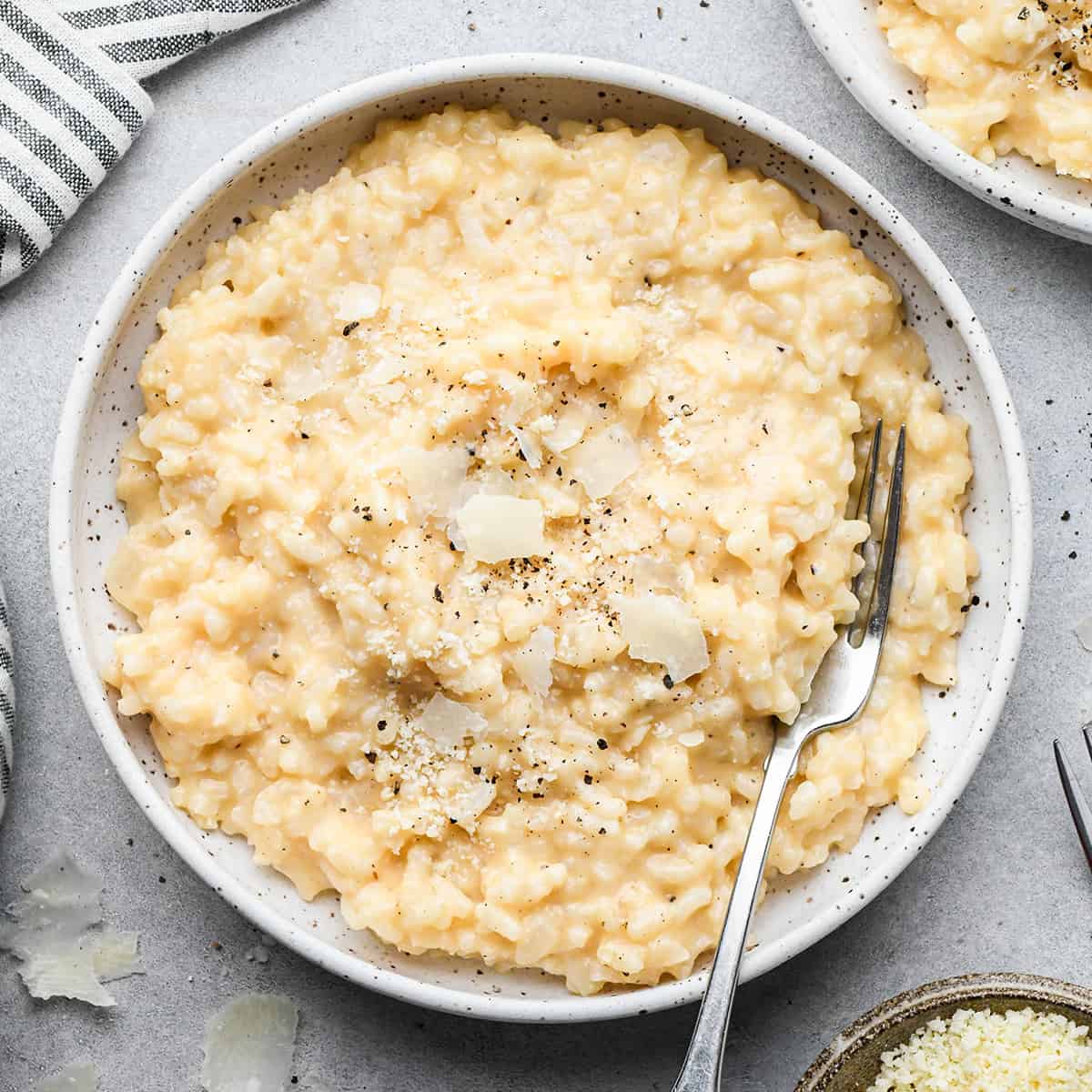 a bowl of risotto topped with parmesan cheese, salt and pepper