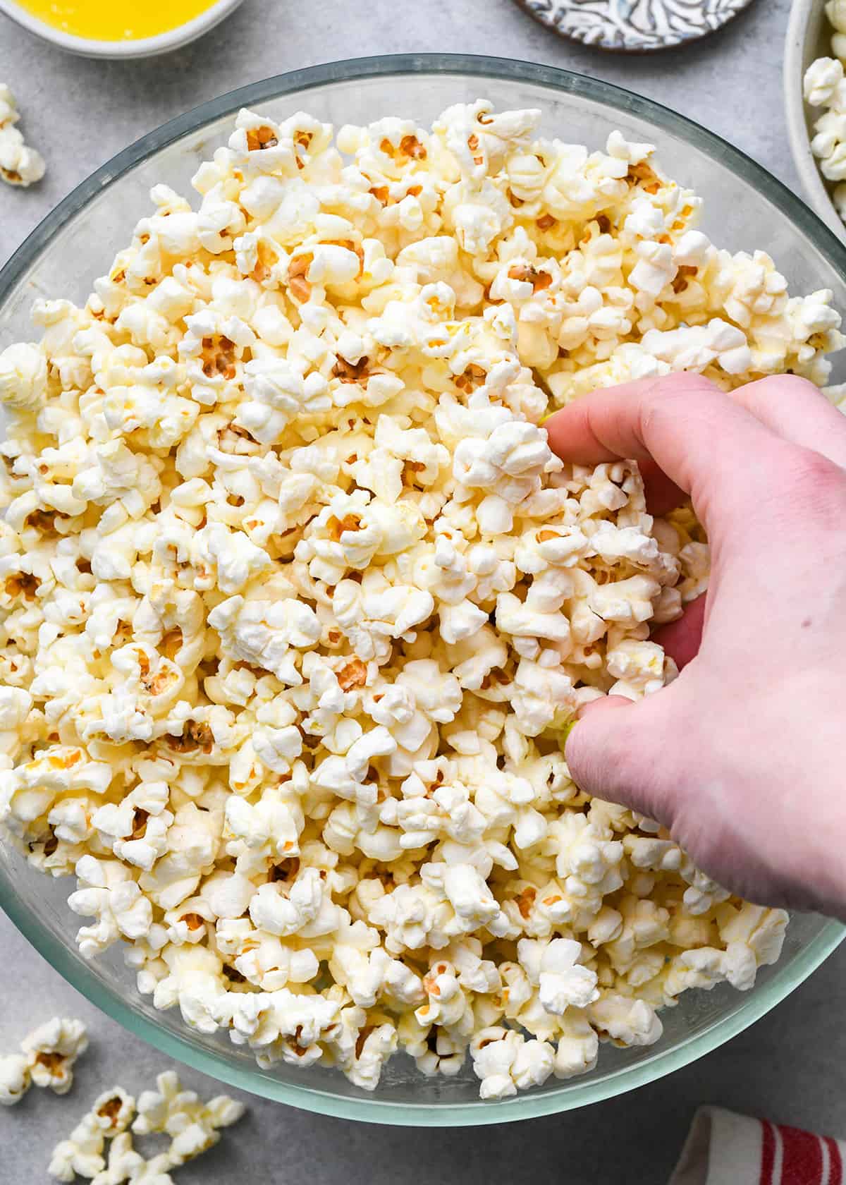 a hand taking a serving of buttered popcorn. 