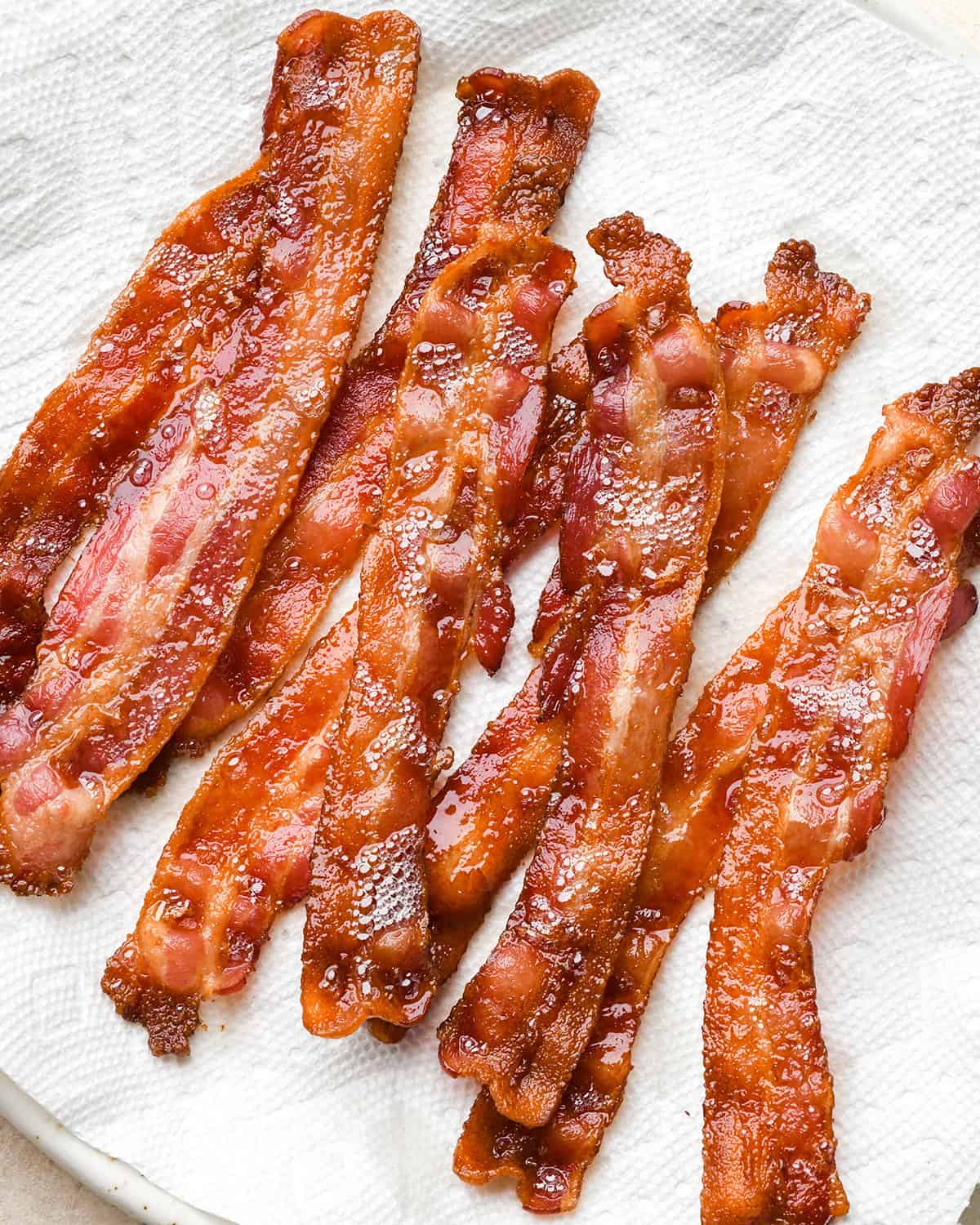 How to Cook Bacon in the Oven - baked bacon on a paper towel lined plate