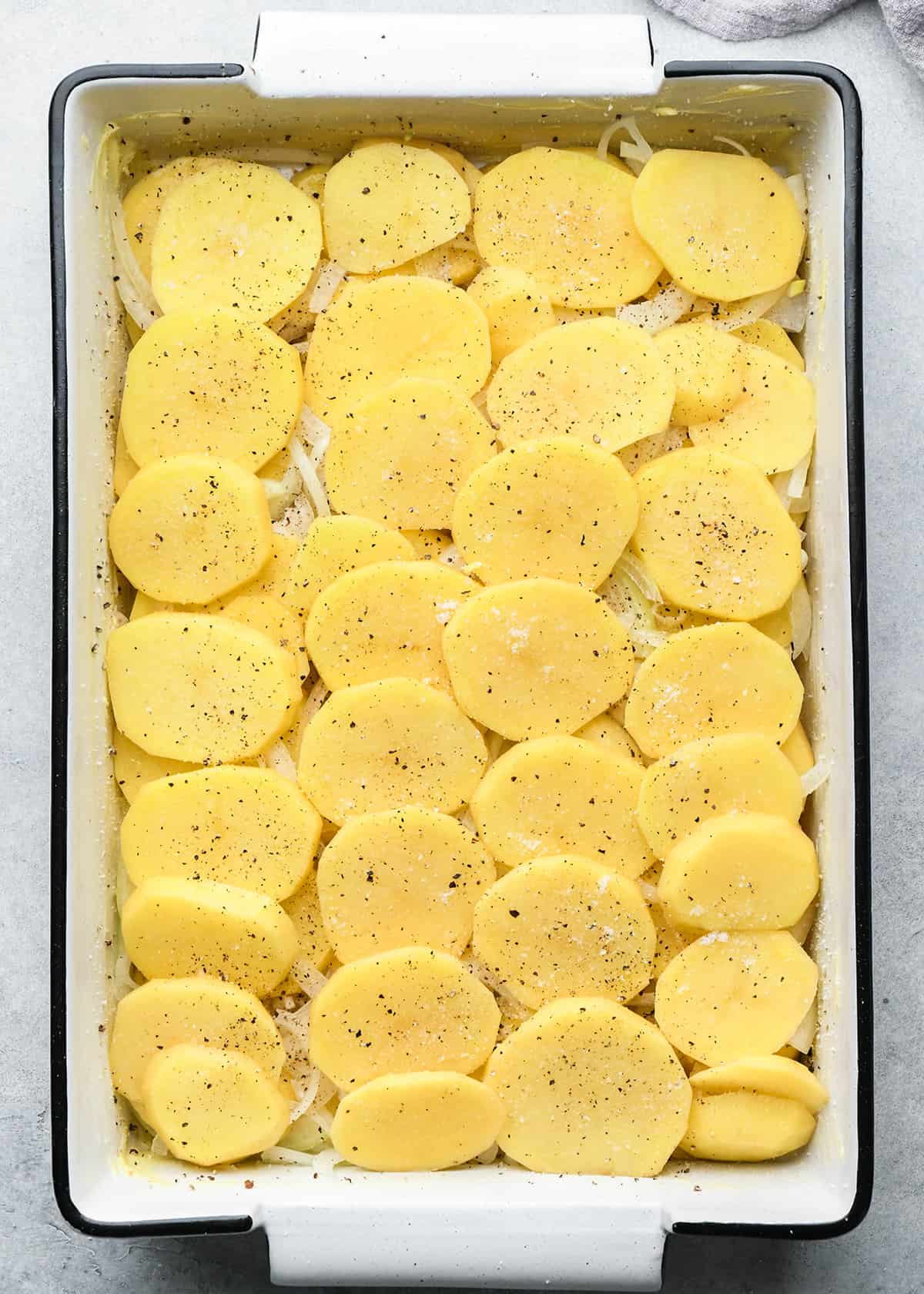 assembling au gratin potatoes in a baking dish