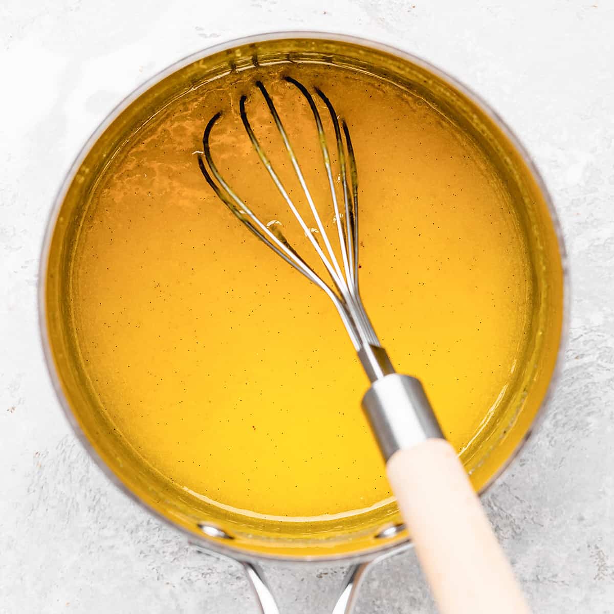 lemon curd being cooked and whisked in a saucepan