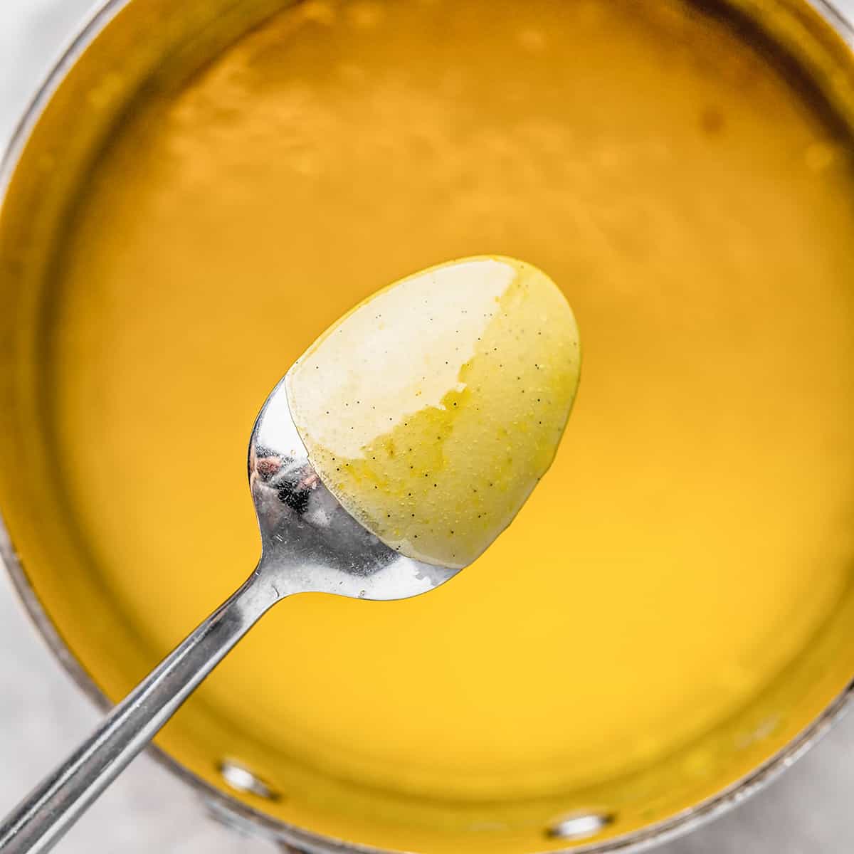 lemon curd coating the back of a spoon over a saucepan