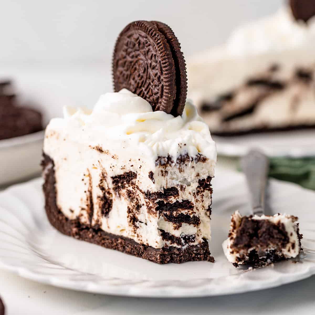 a slice of No Bake Oreo Cheesecake on a plate with a bite taken out of it