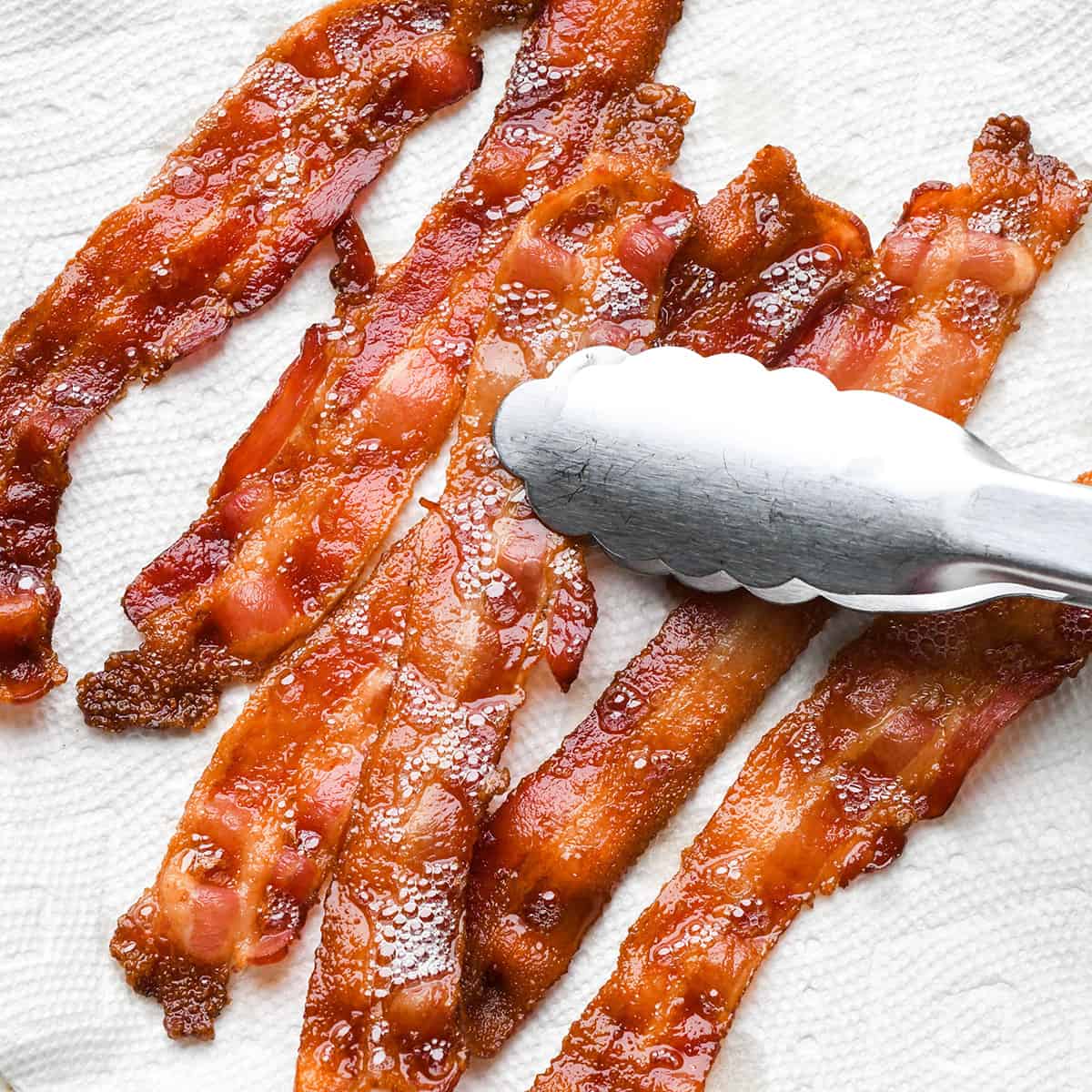 tongs holding Oven Baked Bacon