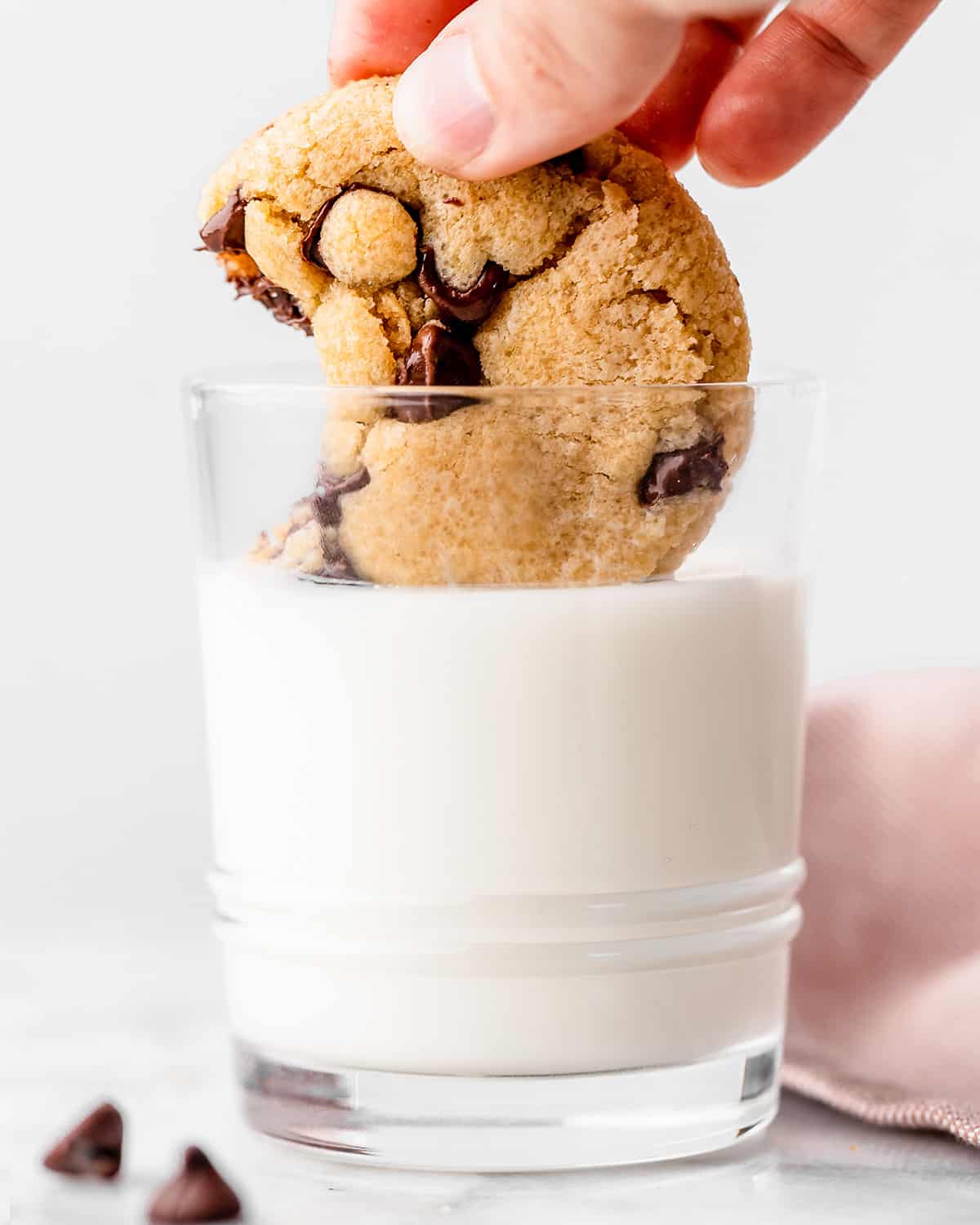 a Small Batch Chocolate Chip Cookie being dipped into a glass of milk