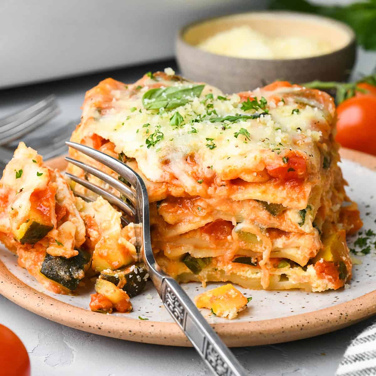 a fork taking a bite of vegetarian lasagna on a plate