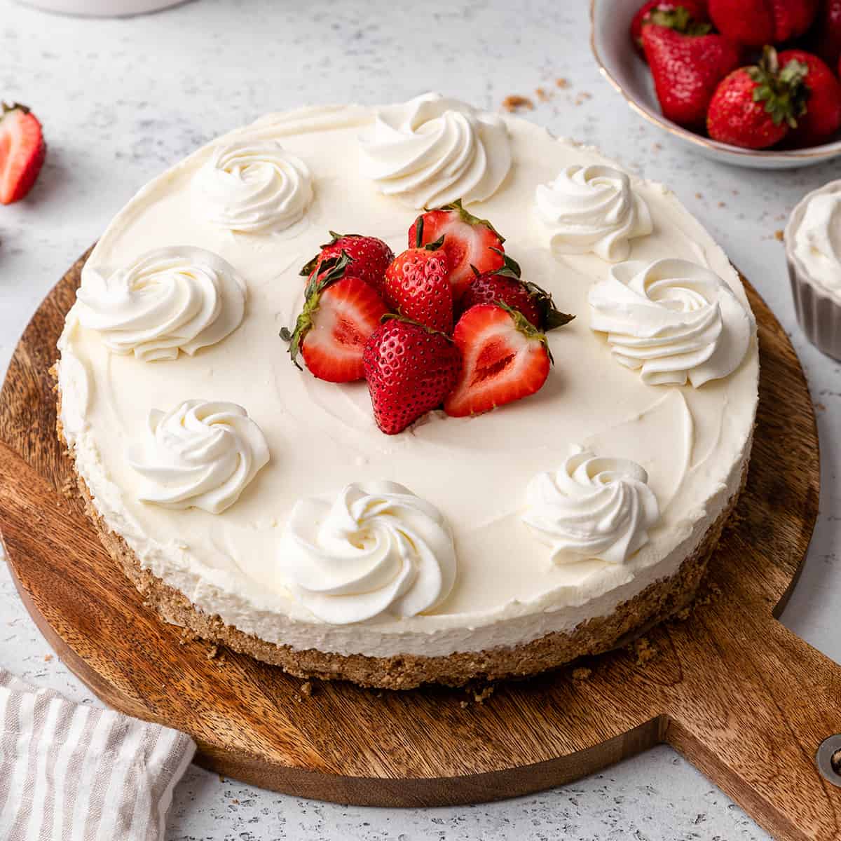 No Bake Cheesecake on a serving plate with whipped cream and strawberries