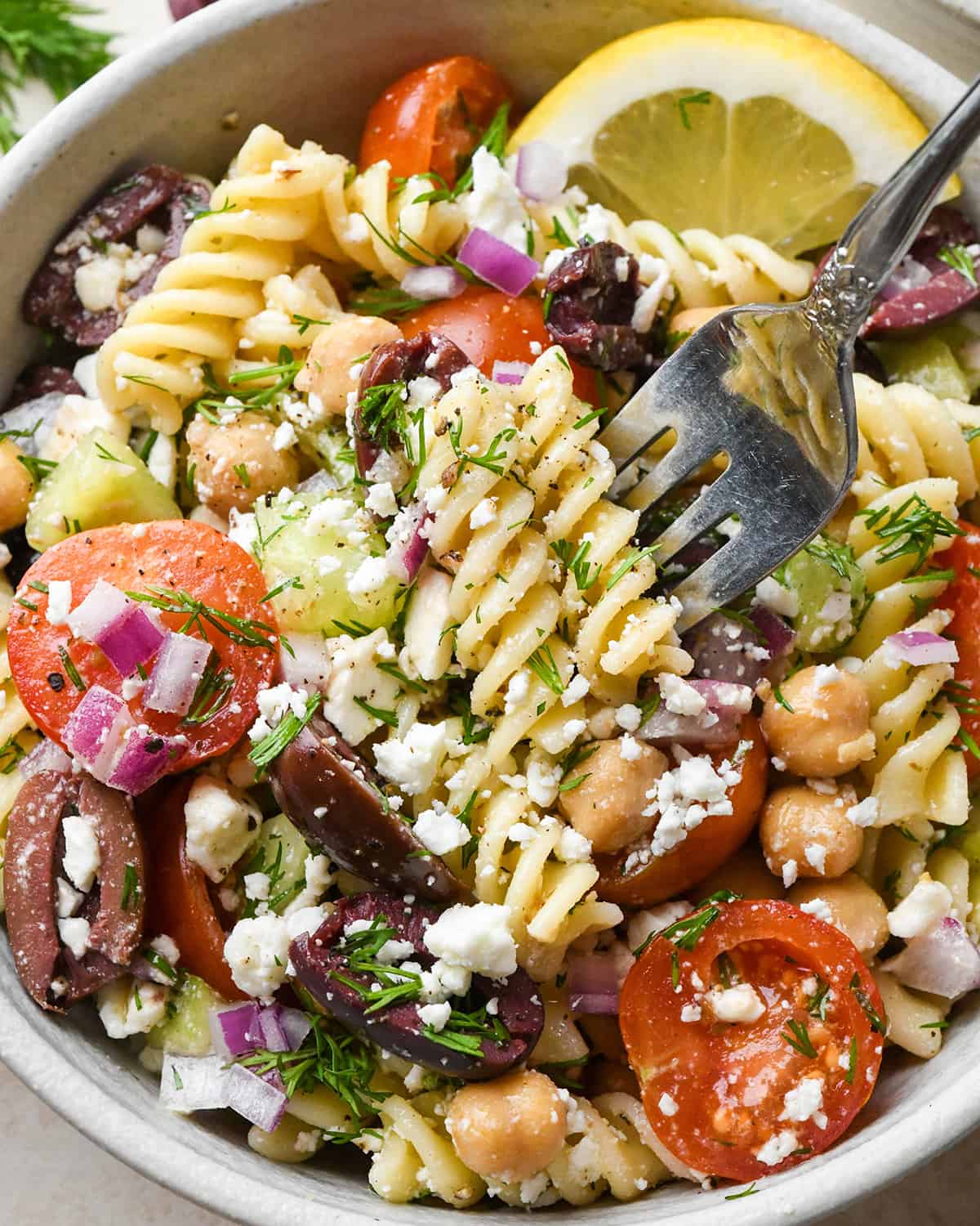 up close photo of a fork taking a bite of Greek Pasta Salad