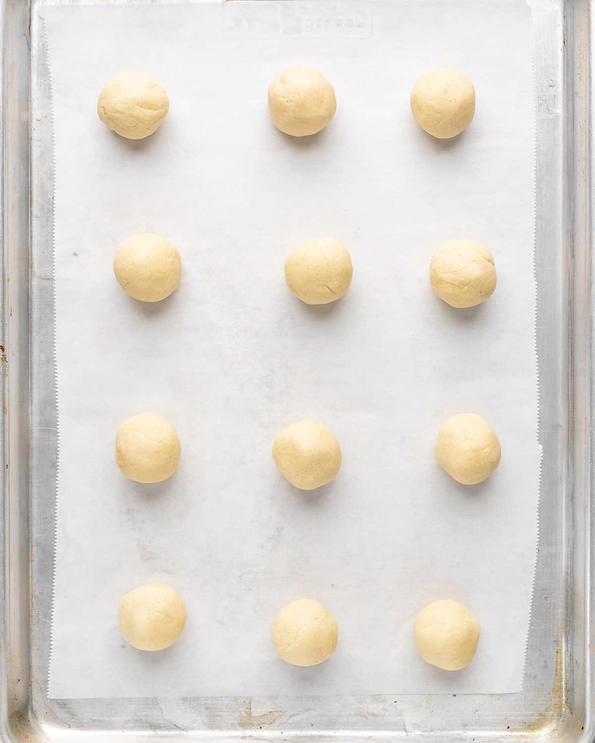 12 round balls of dough on a baking sheet