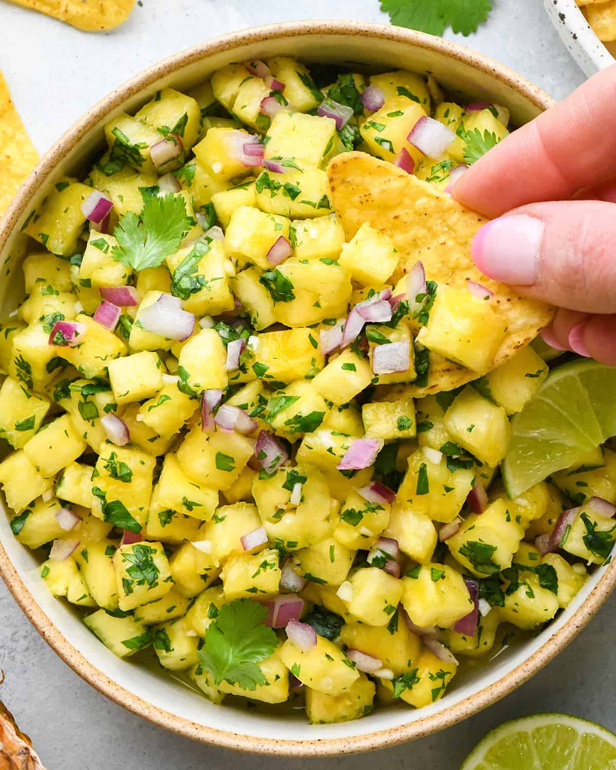 a chip scooping Pineapple Salsa out of a bowl