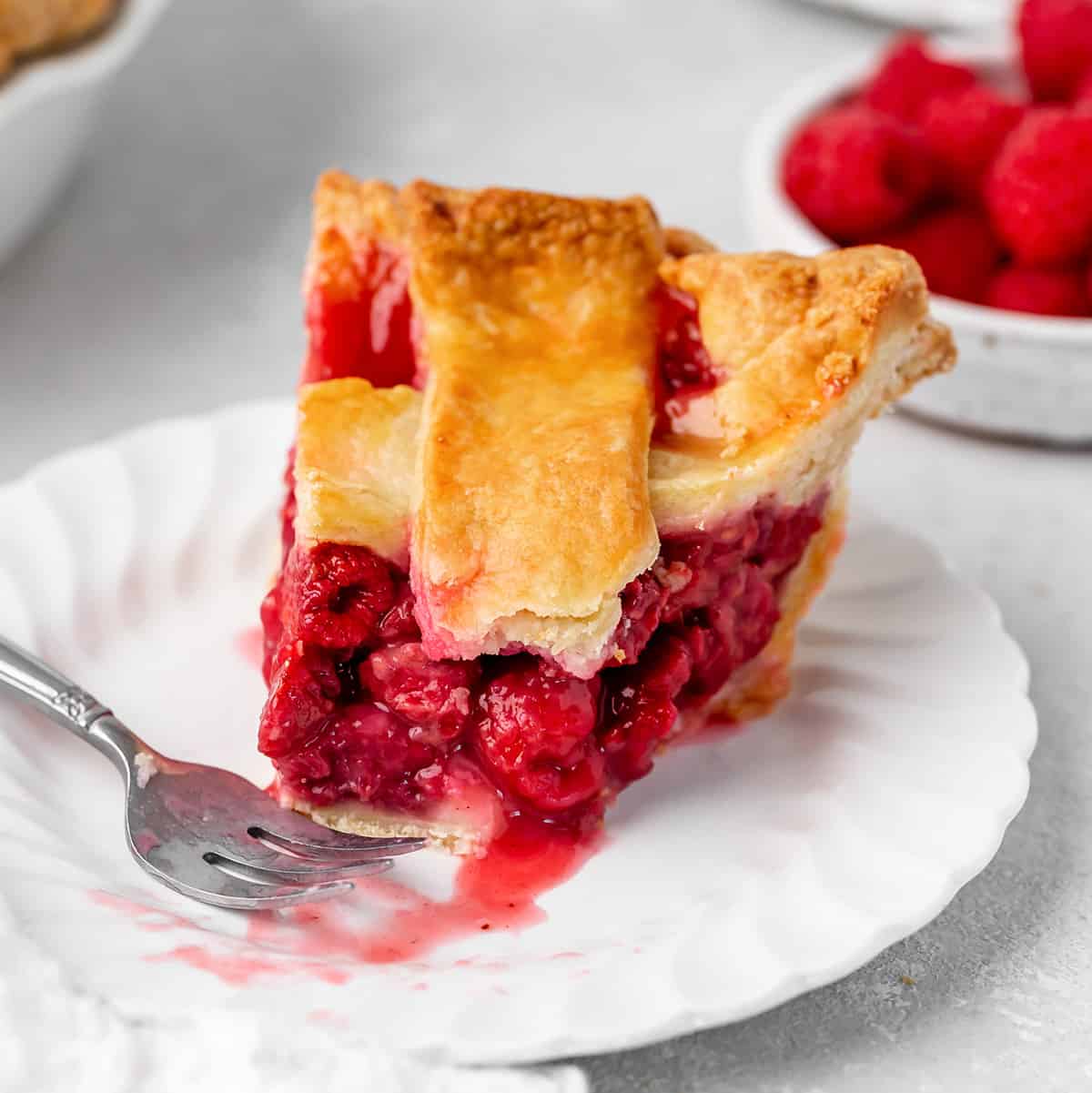 a slice of Raspberry Pie on a plate with a bite taken out of it