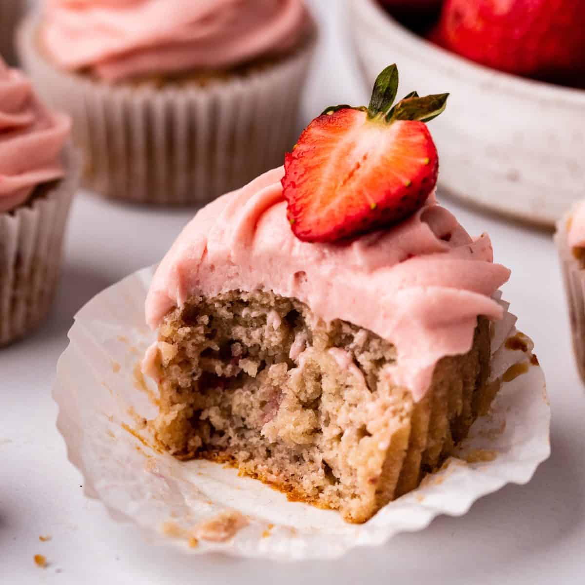 a frosted Strawberry Cupcake with a bite taken out of it