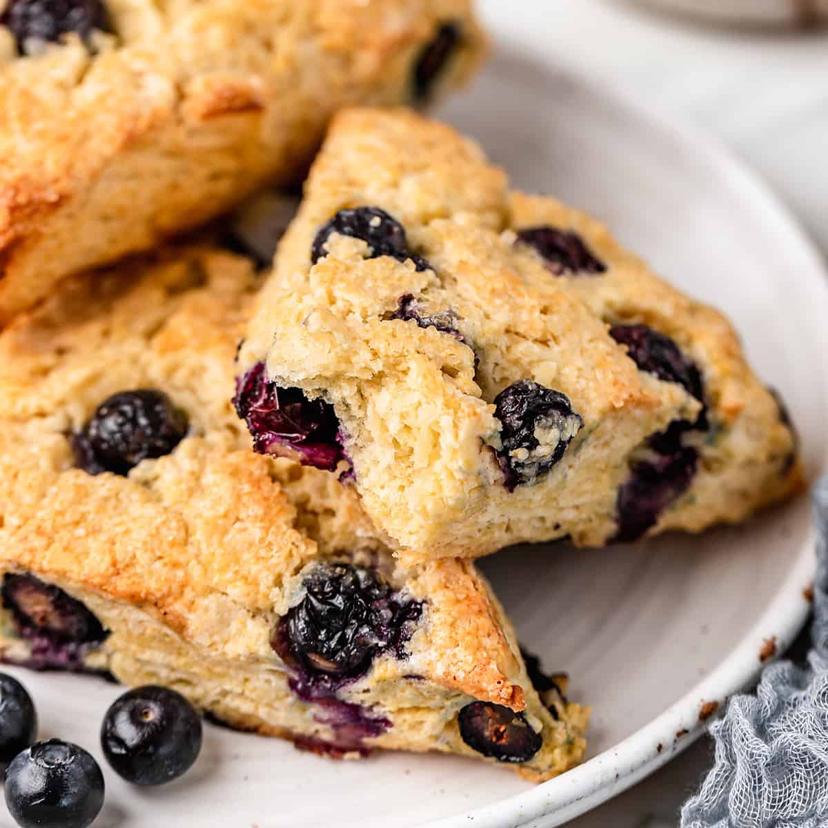 blueberry scones on a plate, one has a bite taken out of it