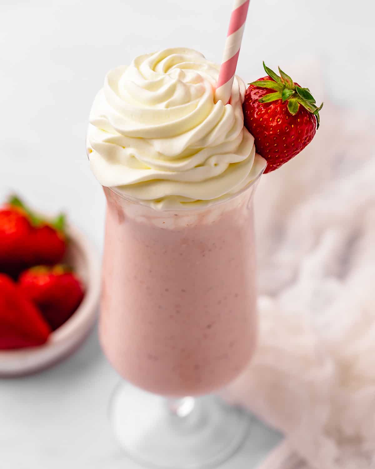 up close photo of Strawberry Milkshake in a glass topped with whipped cream
