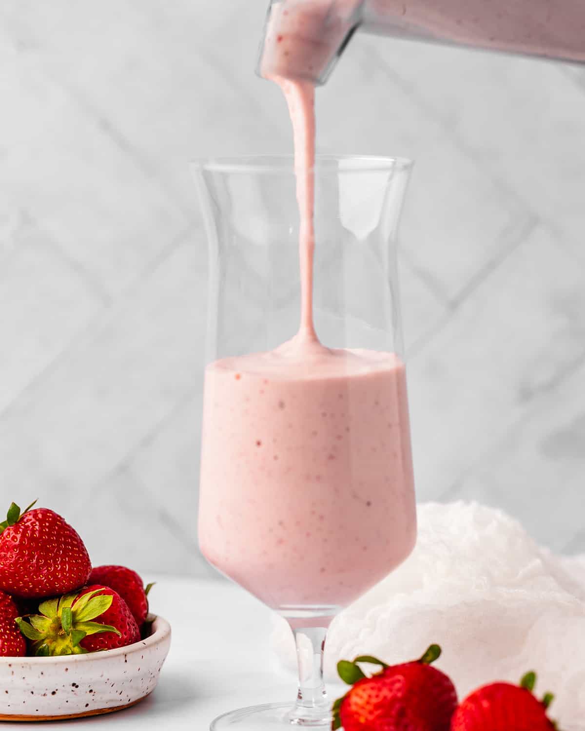 Strawberry Milkshake being poured into a glass