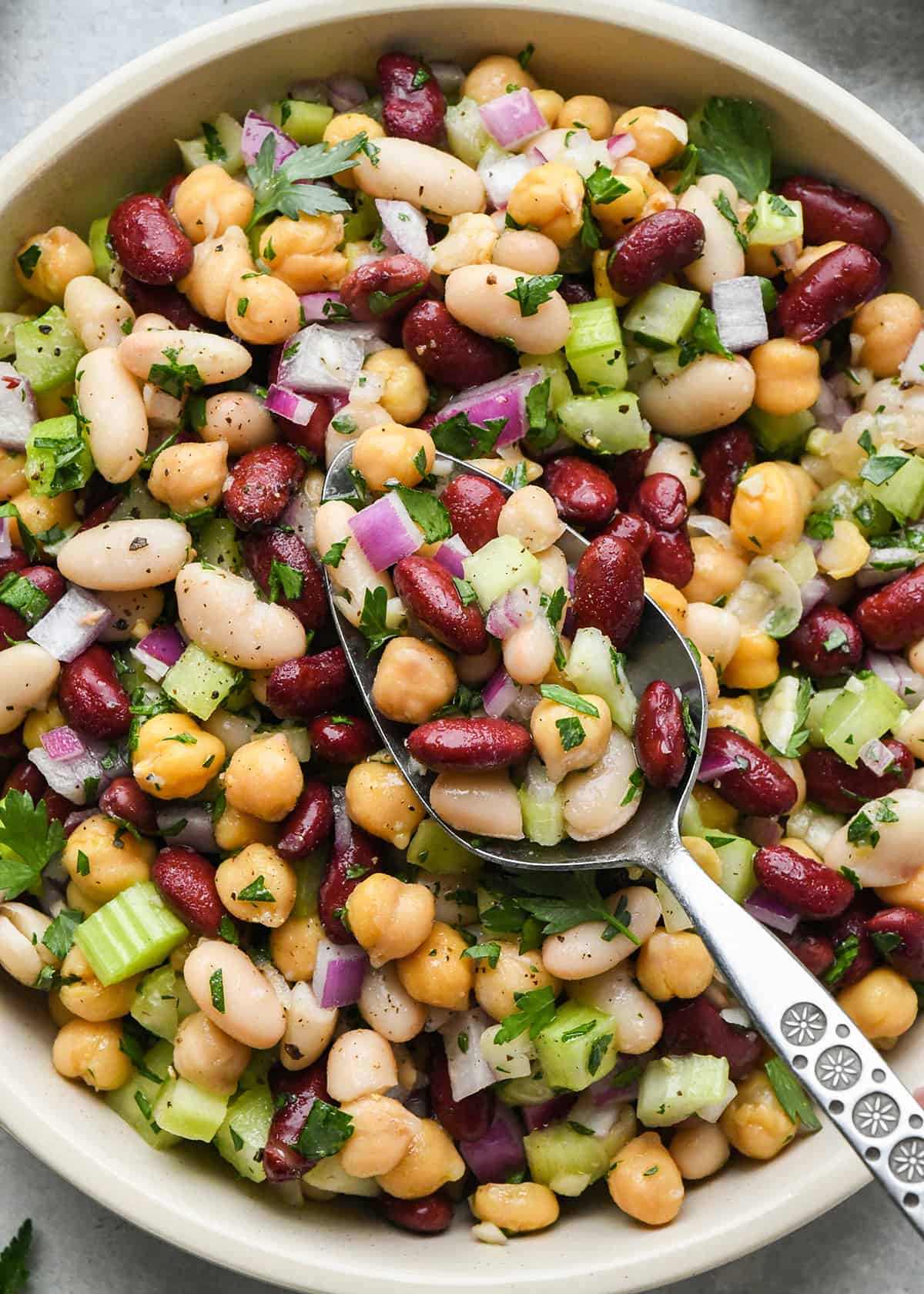 up close photo of three bean salad in a bowl with a spoon 