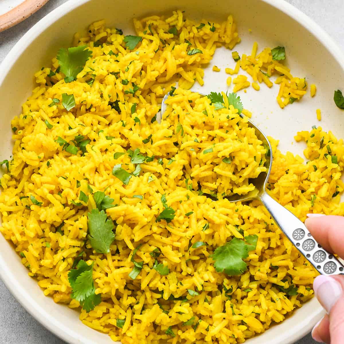 yellow Rice garnished with cilantro in a bowl with a spoon