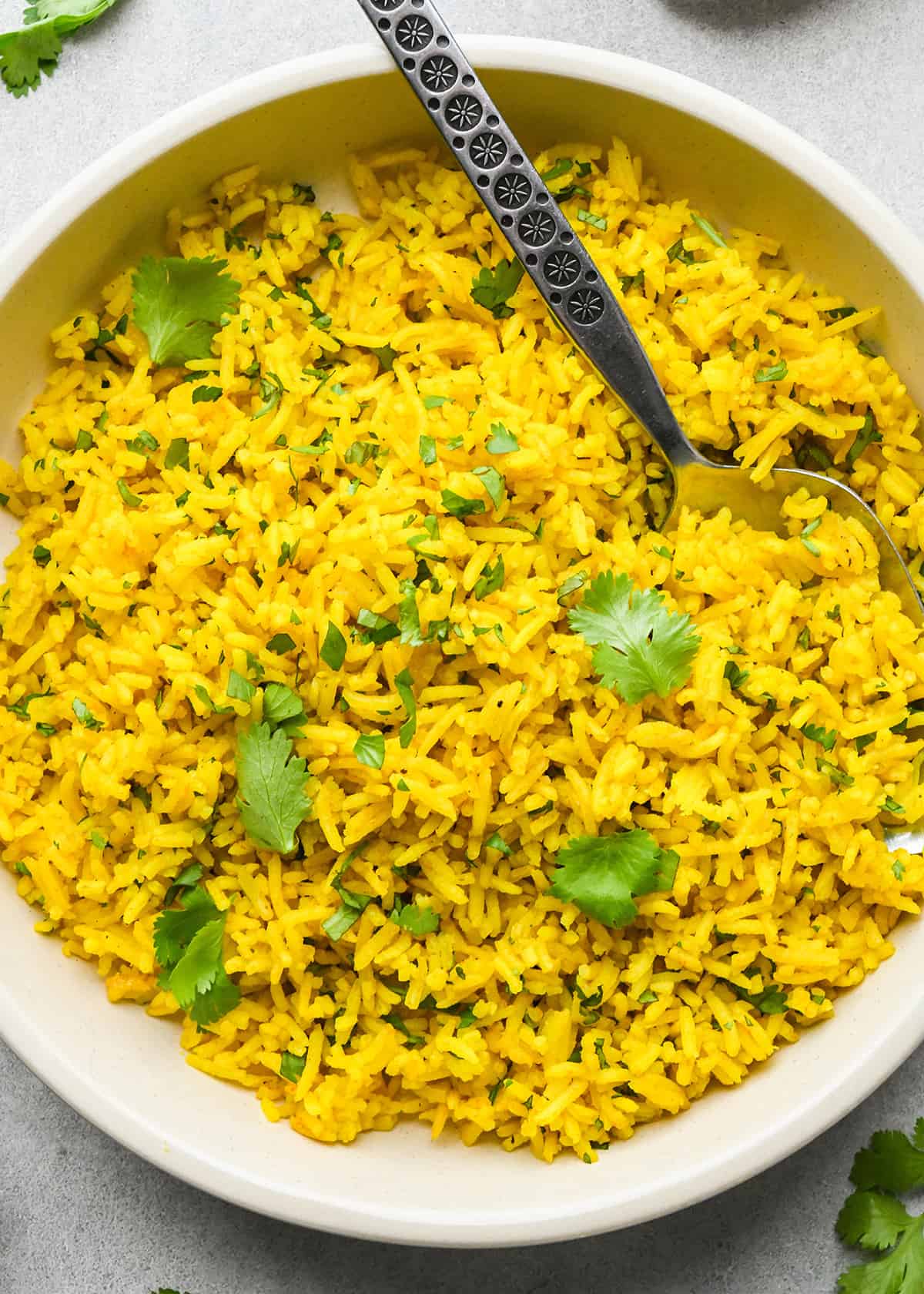 Turmeric Rice in a bowl with a spoon garnished with cilantro