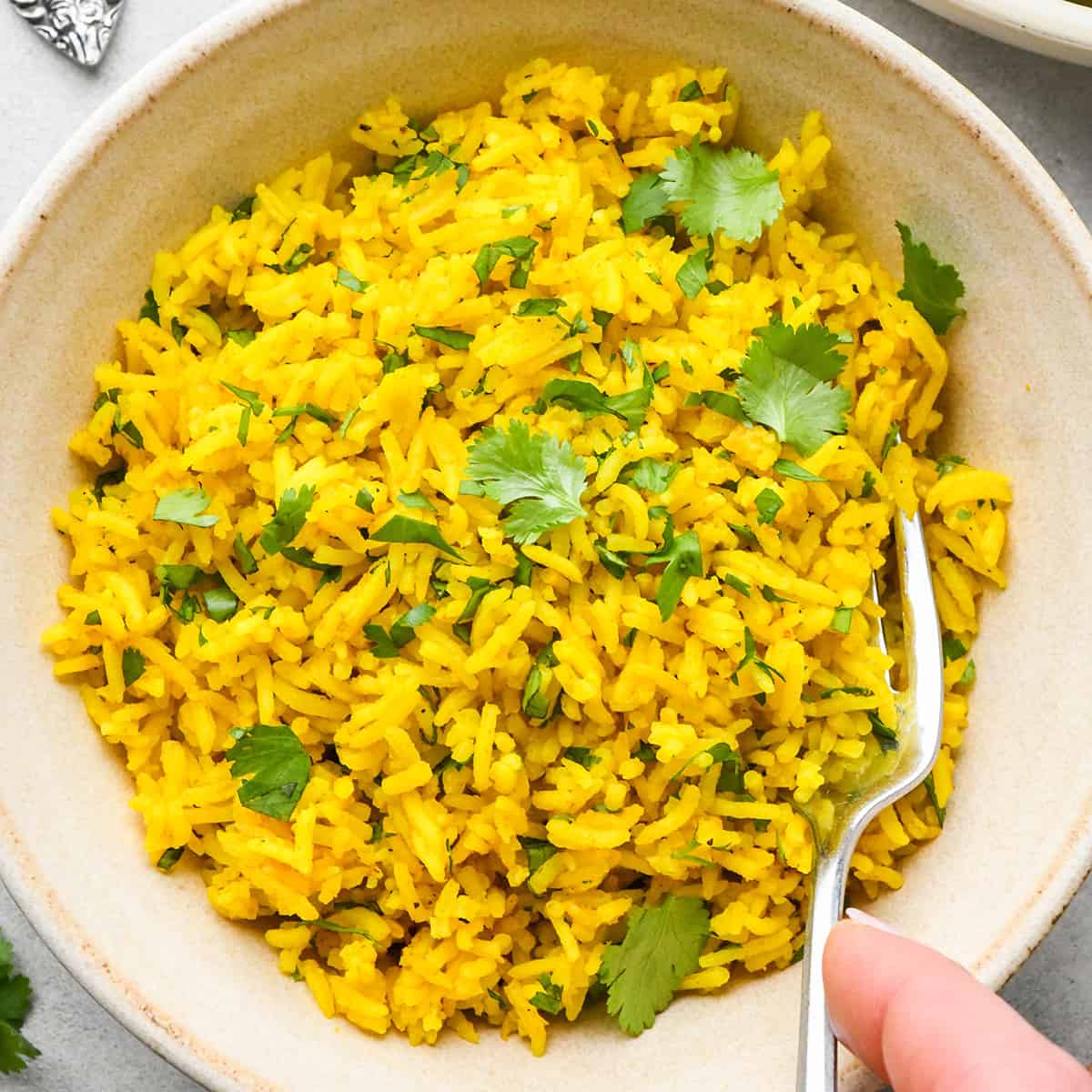 yellow Rice garnished with cilantro in a bowl with a fork