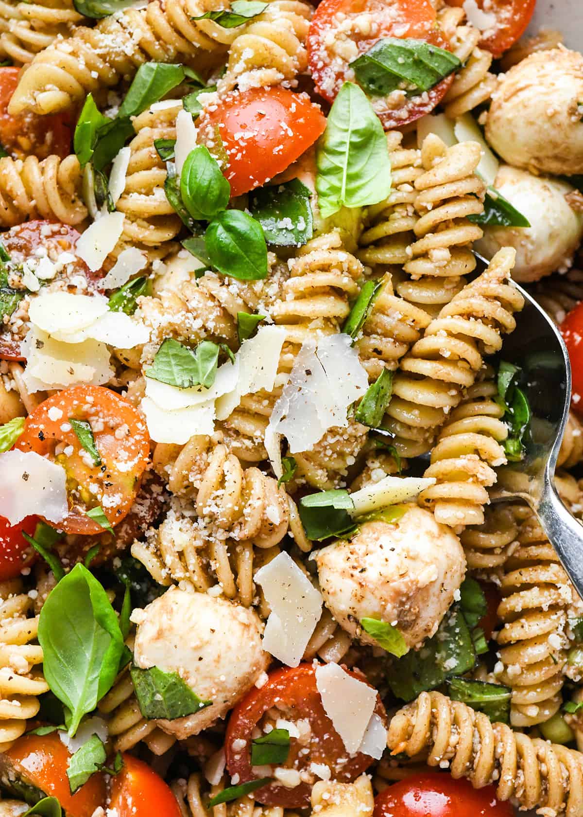 a spoon taking a scoop of Caprese Pasta Salad