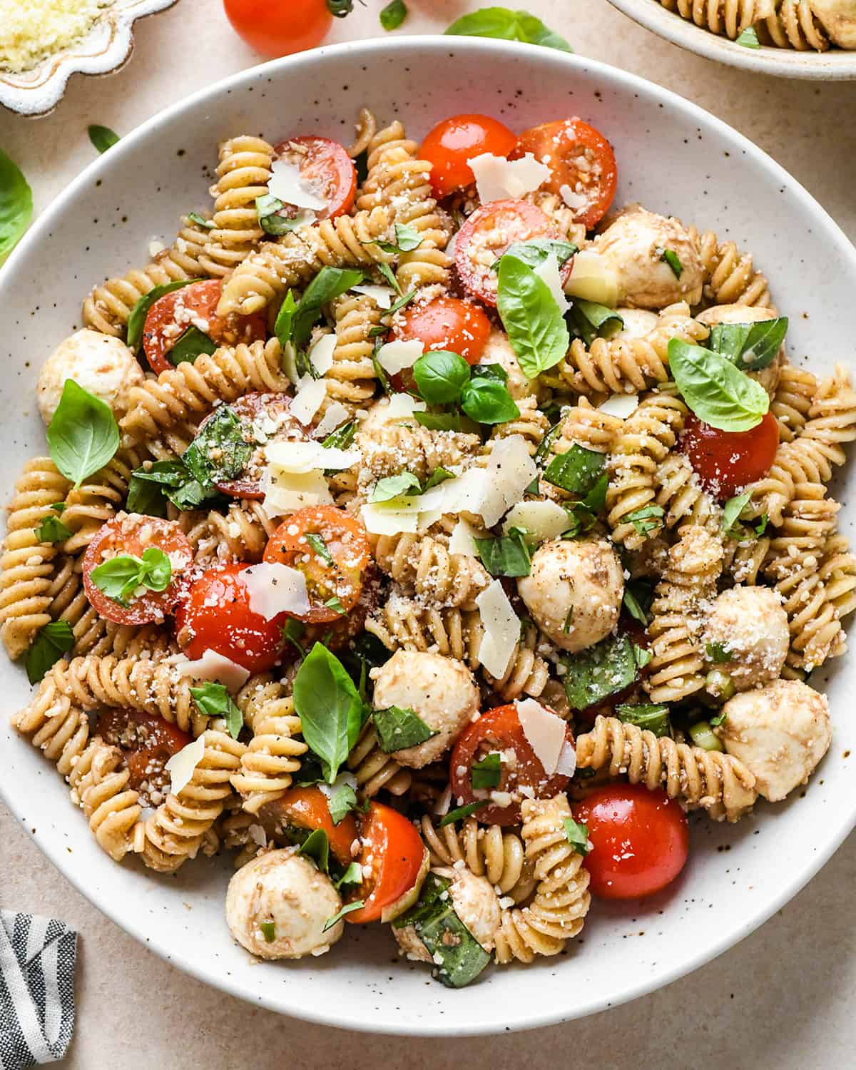 Caprese Pasta Salad in a bowl garnished with fresh basil and parmesan cheese