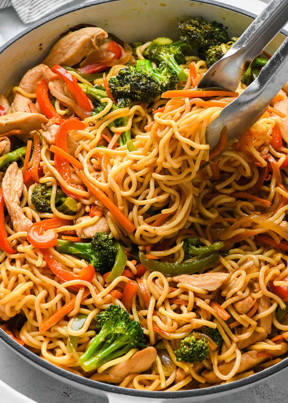 tongs taking a serving of Chicken Lo Mein  out of a pot