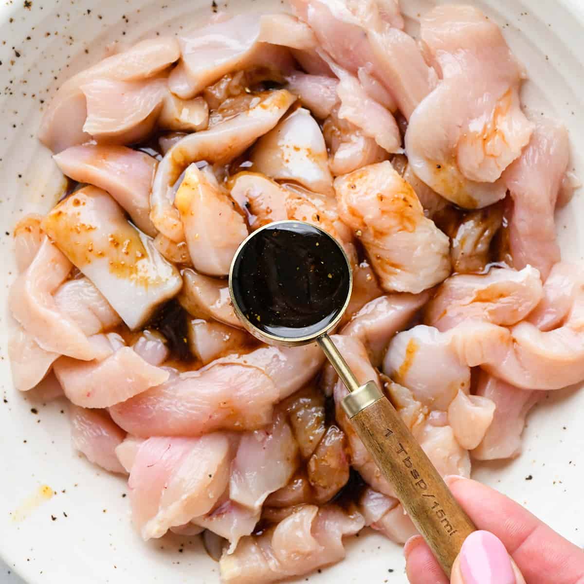 chicken marinade ingredients being added to slice chicken