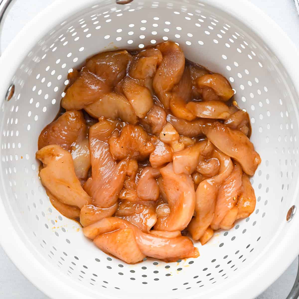 marinaded chicken in a colander