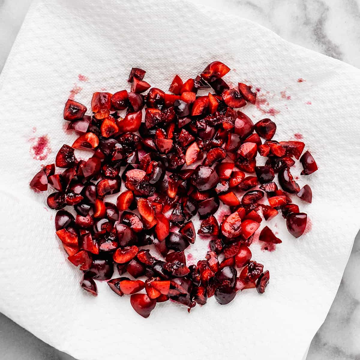 chopped and pitted cherries on a paper towel drying out to use in this Cherry Cookies recipe