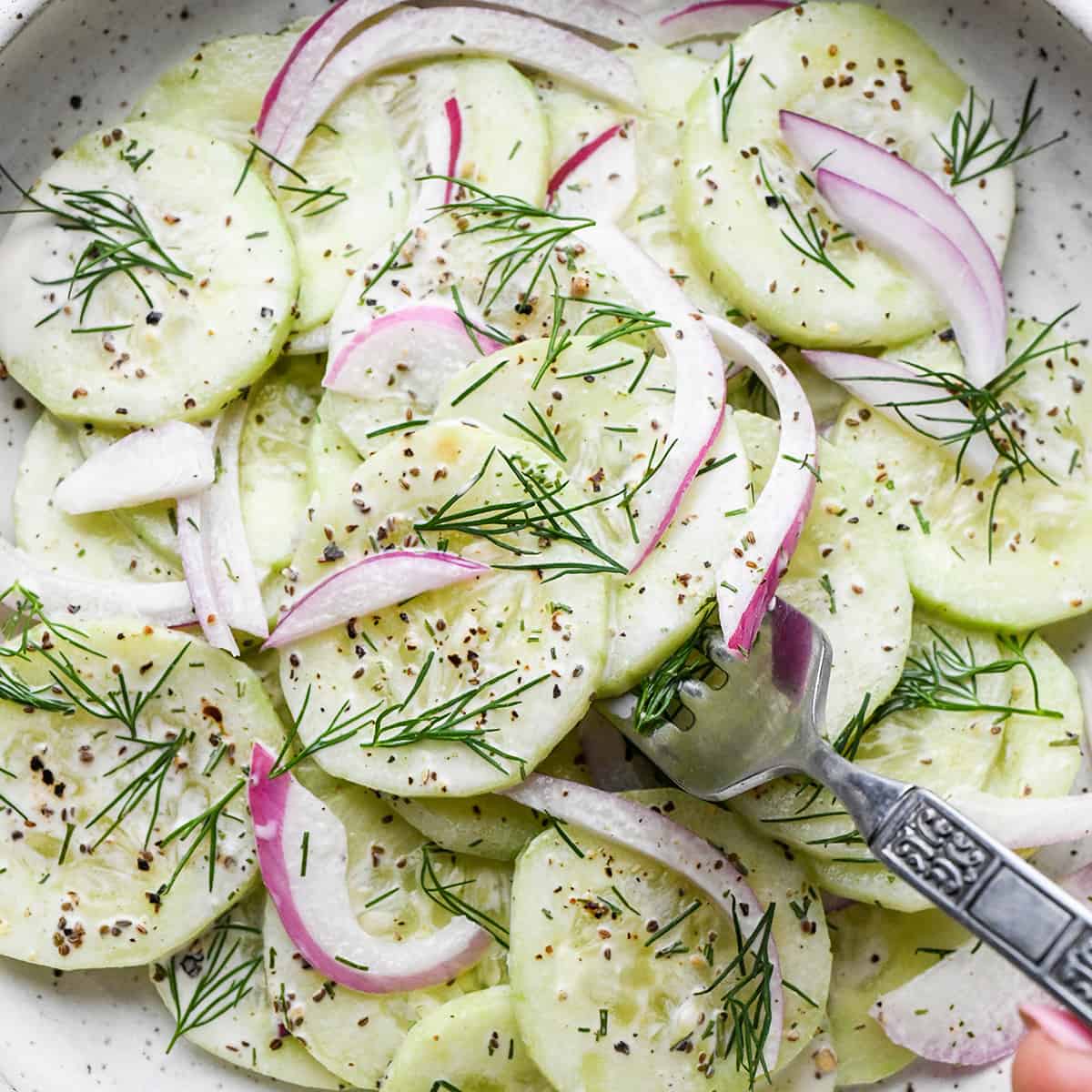 a fork taking a bite of Cucumber Salad on a plate