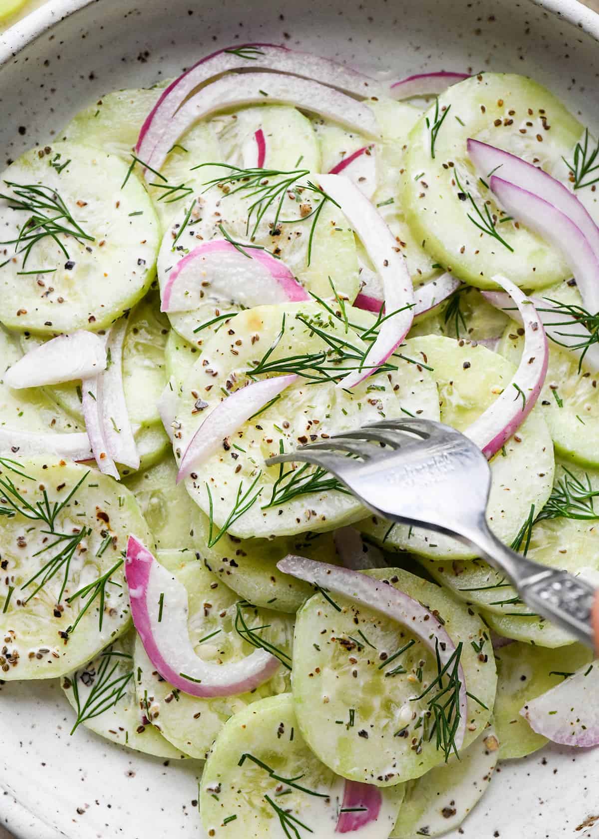 a fork taking a bite of cucumber salad 