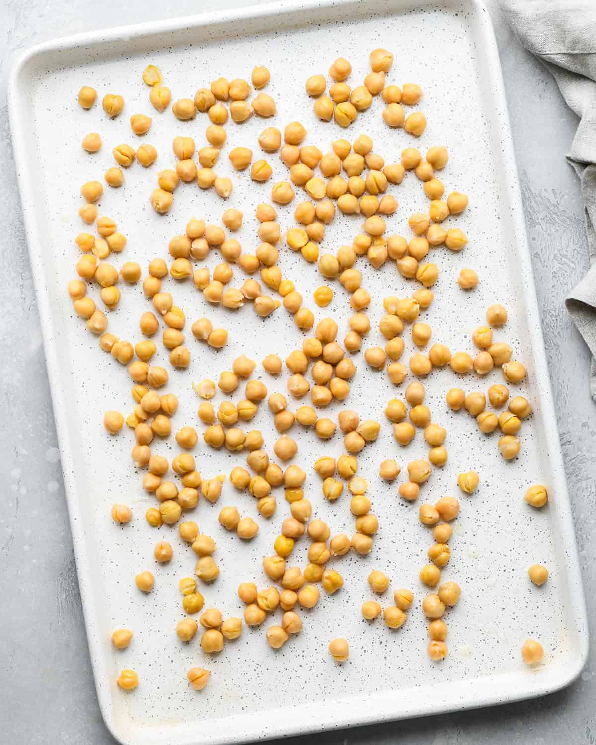 making roasted chickpeas recipe - dry chickpeas on a white baking sheet before roasting