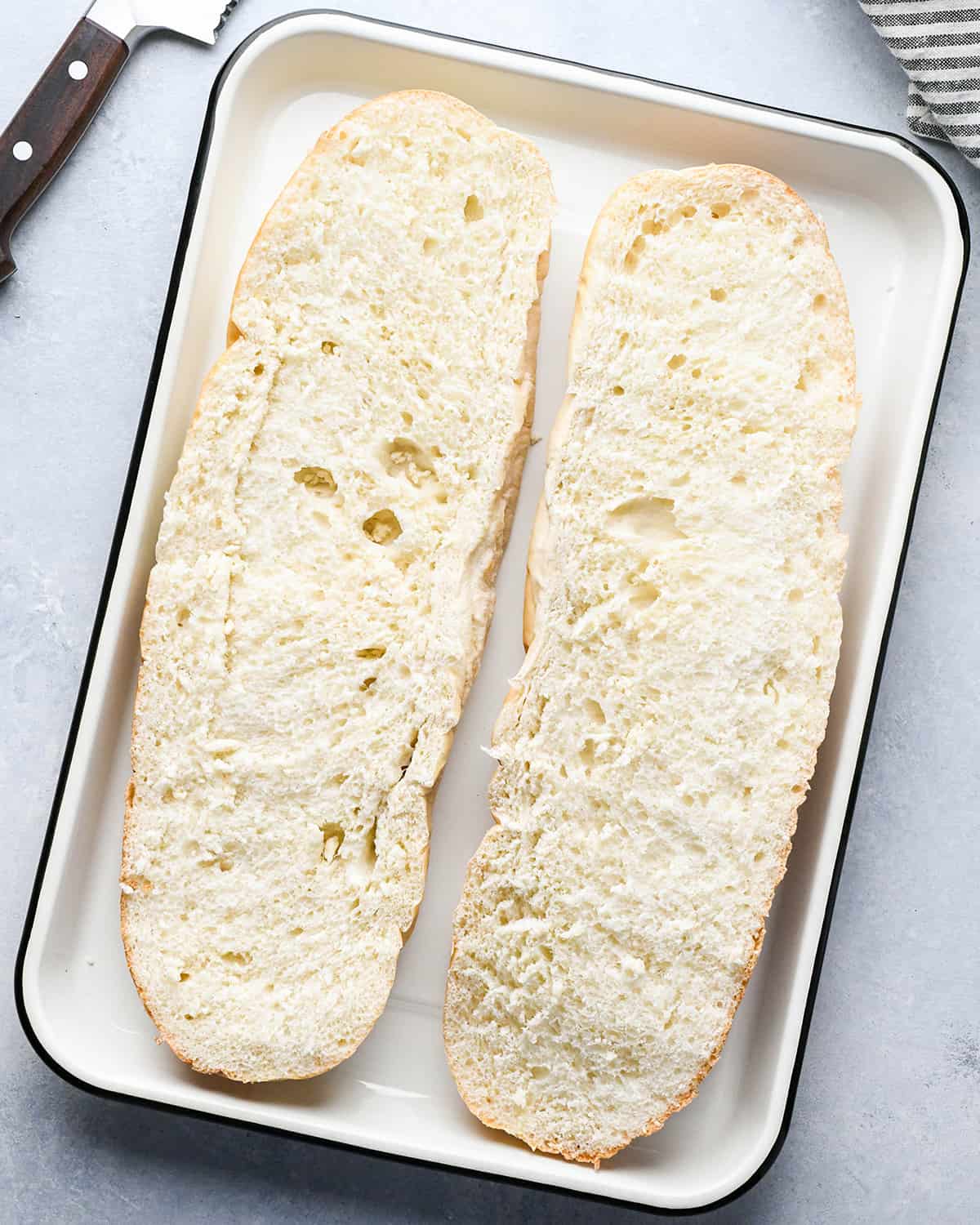 How to Make French Bread Pizza - french bread cut in half lengthwise on a baking sheet