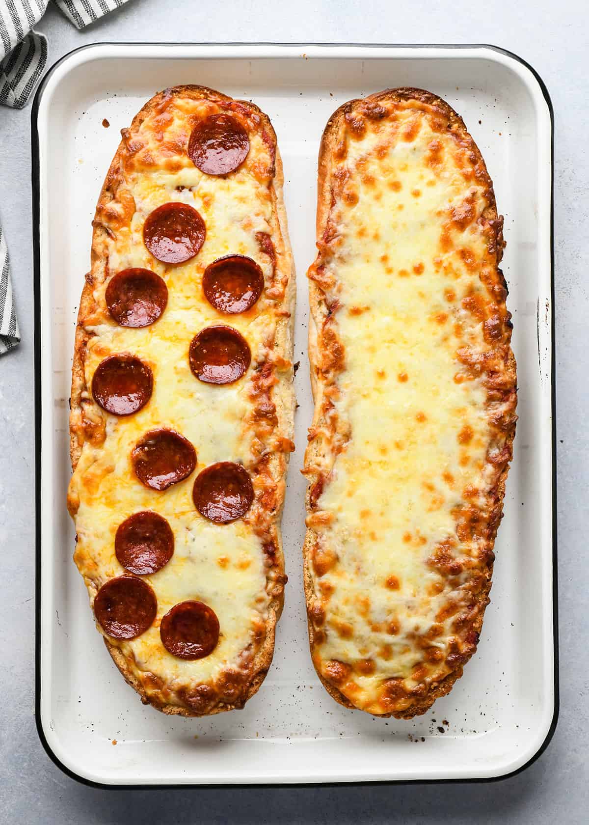 french bread pizza on a baking sheet after baking. left has pepperoni, right is cheese.