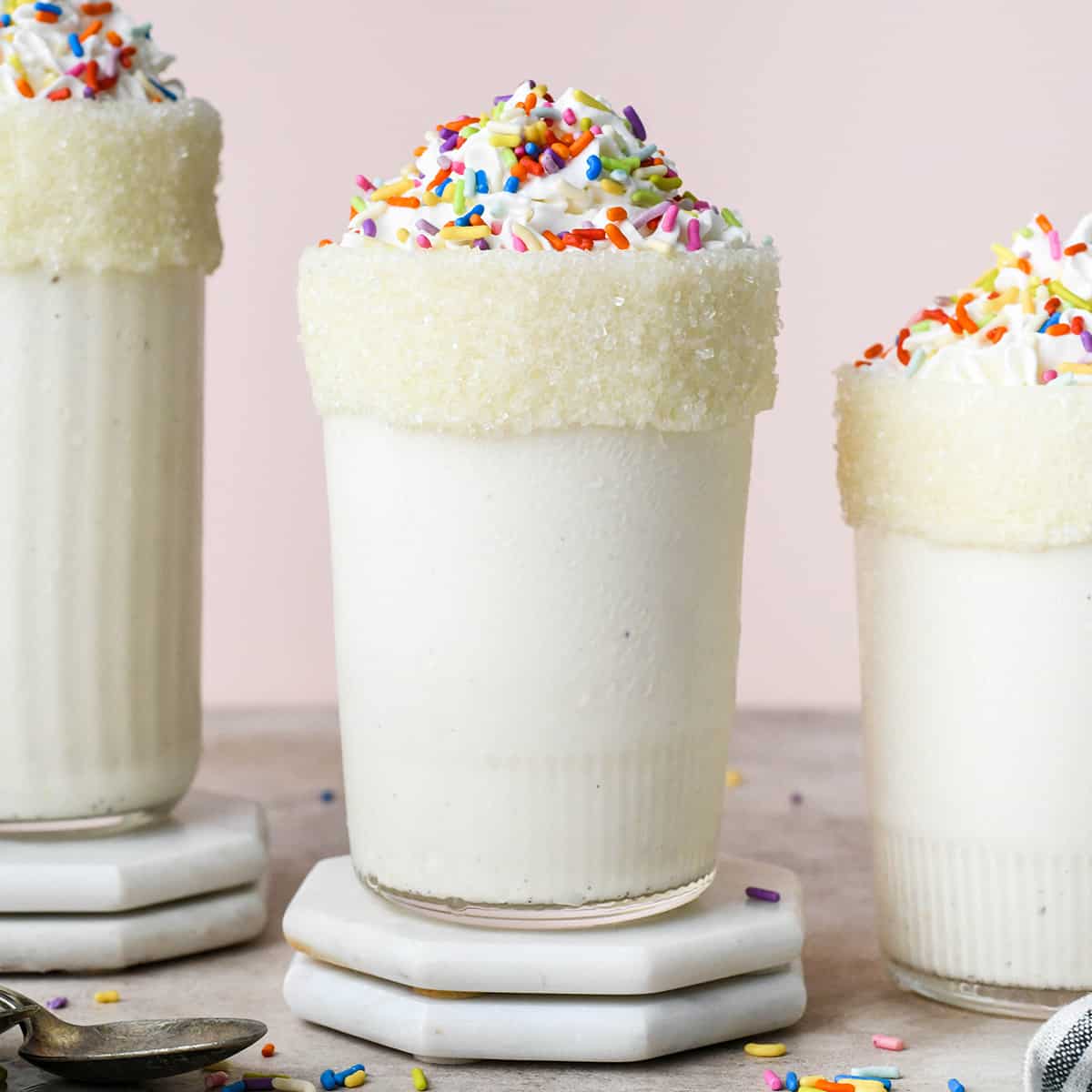 Vanilla Milkshake in 3 glasses with whipped cream and sprinkles