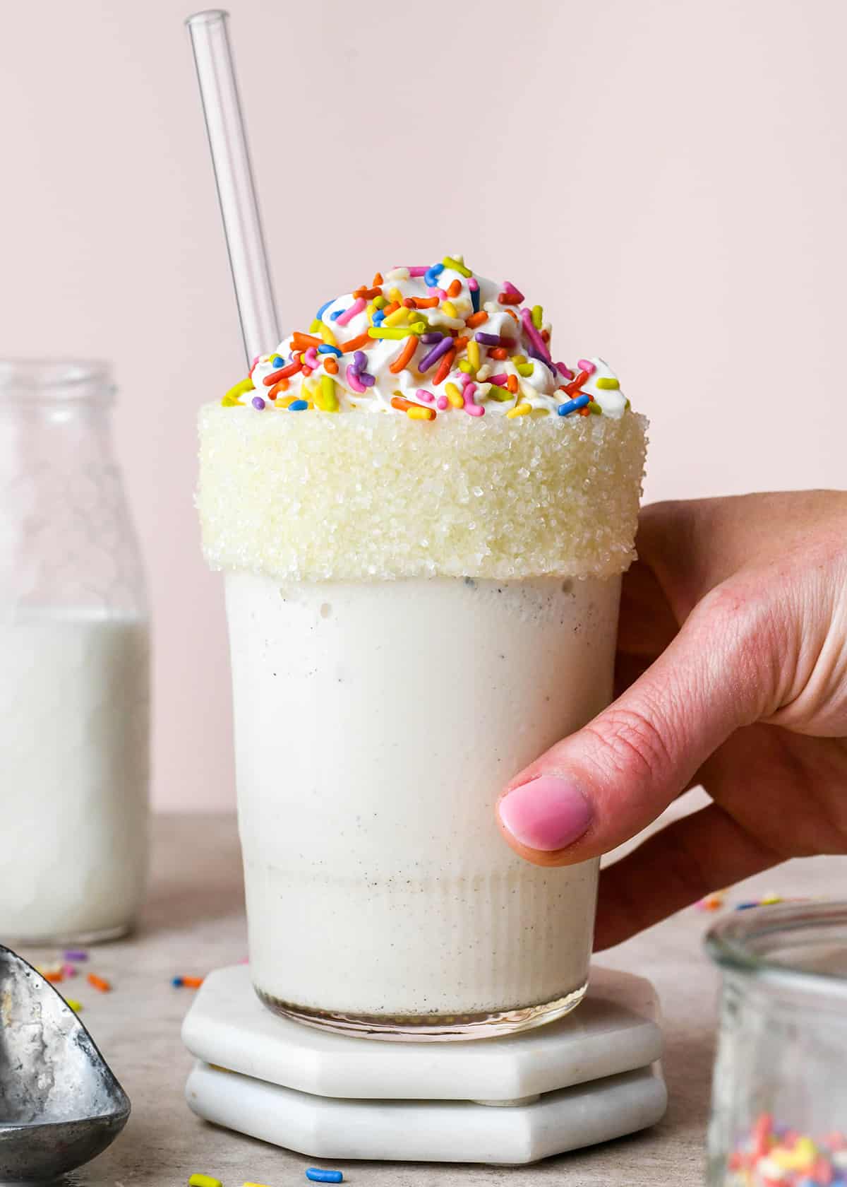 Vanilla Milkshake in a glass topped with whipped cream and sprinkles