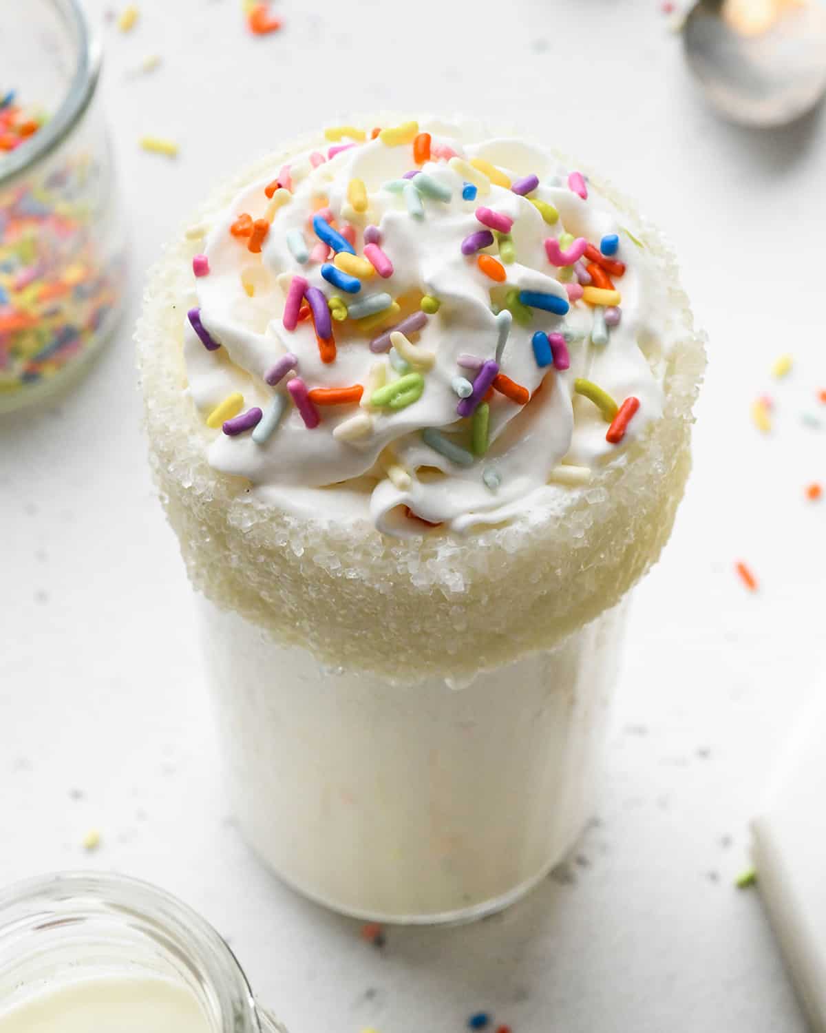 Vanilla Milkshake in a glass topped with whipped cream and sprinkles