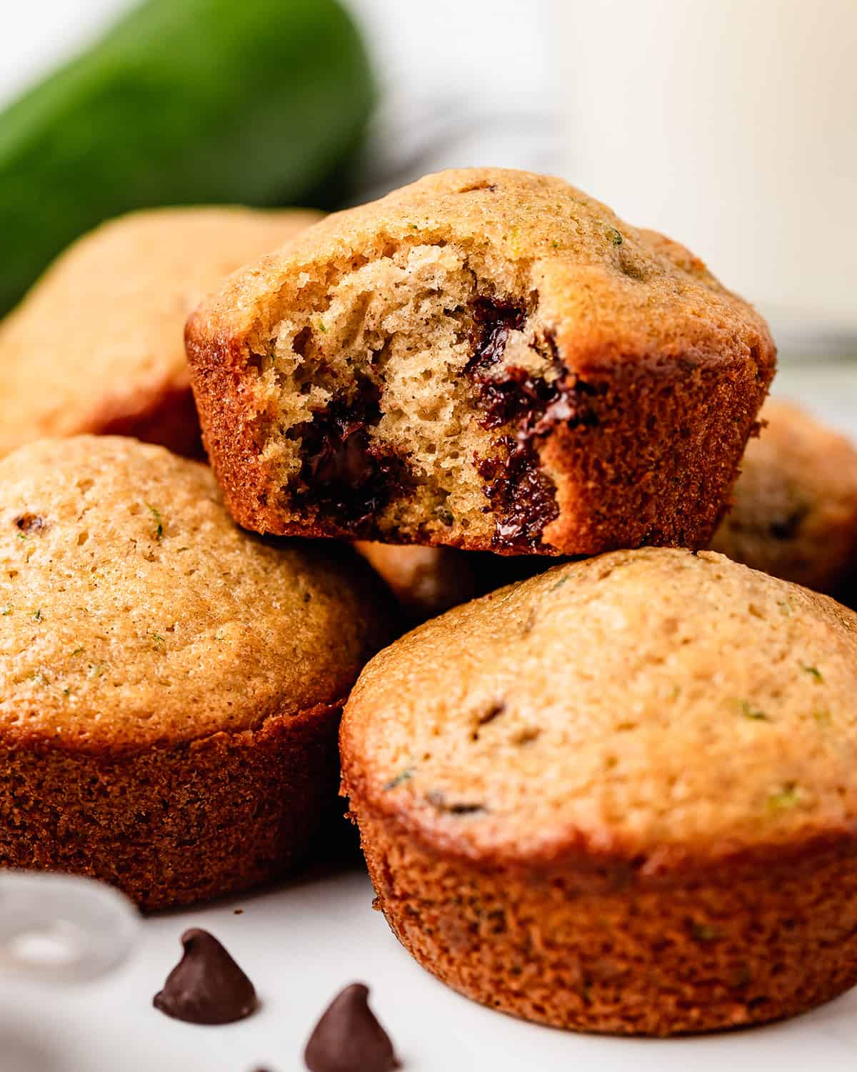 a Zucchini Chocolate Chip Muffin with a bite taken out of it on top of other muffins