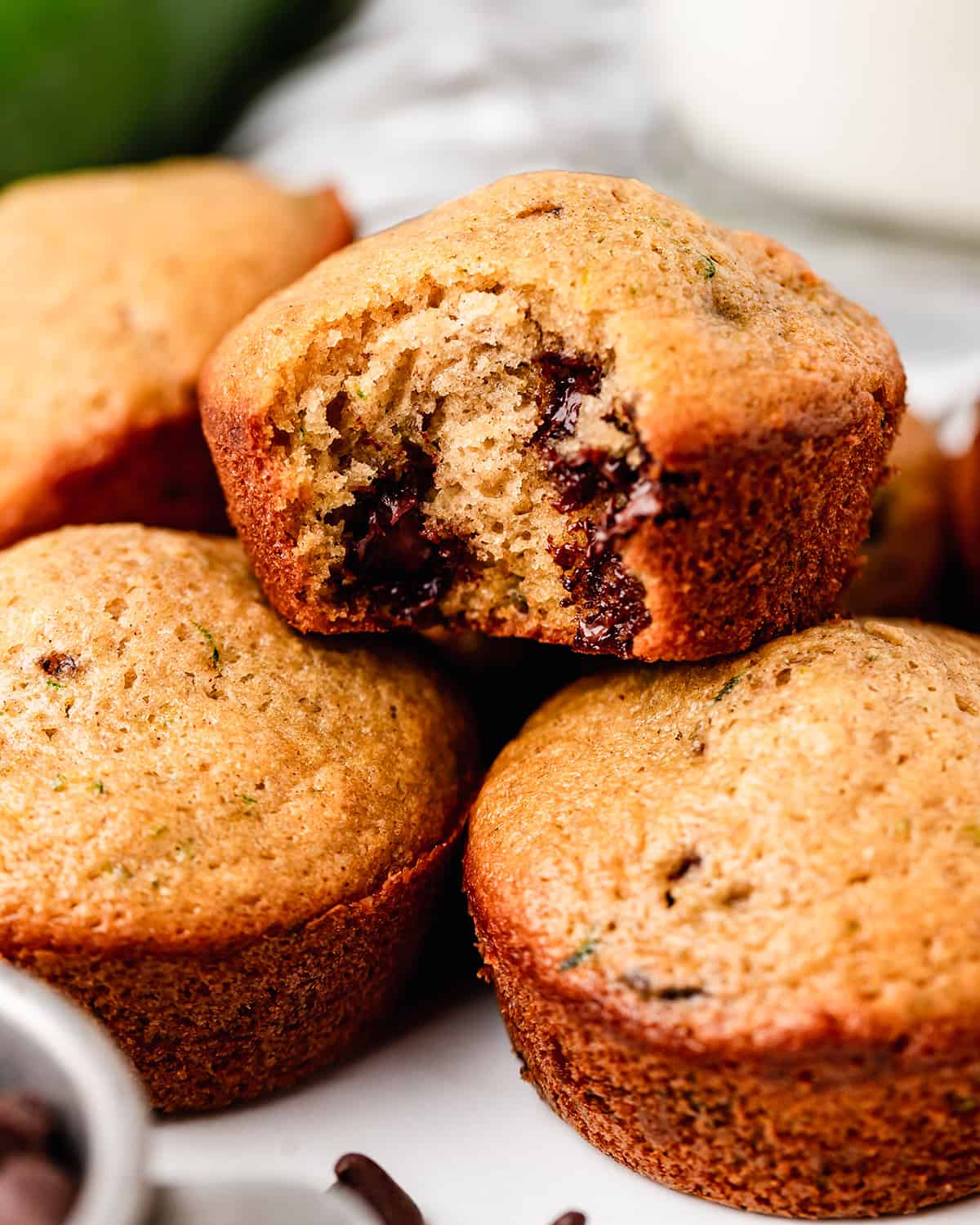 4 Zucchini Chocolate Chip Muffins, one with a bite taken out of it