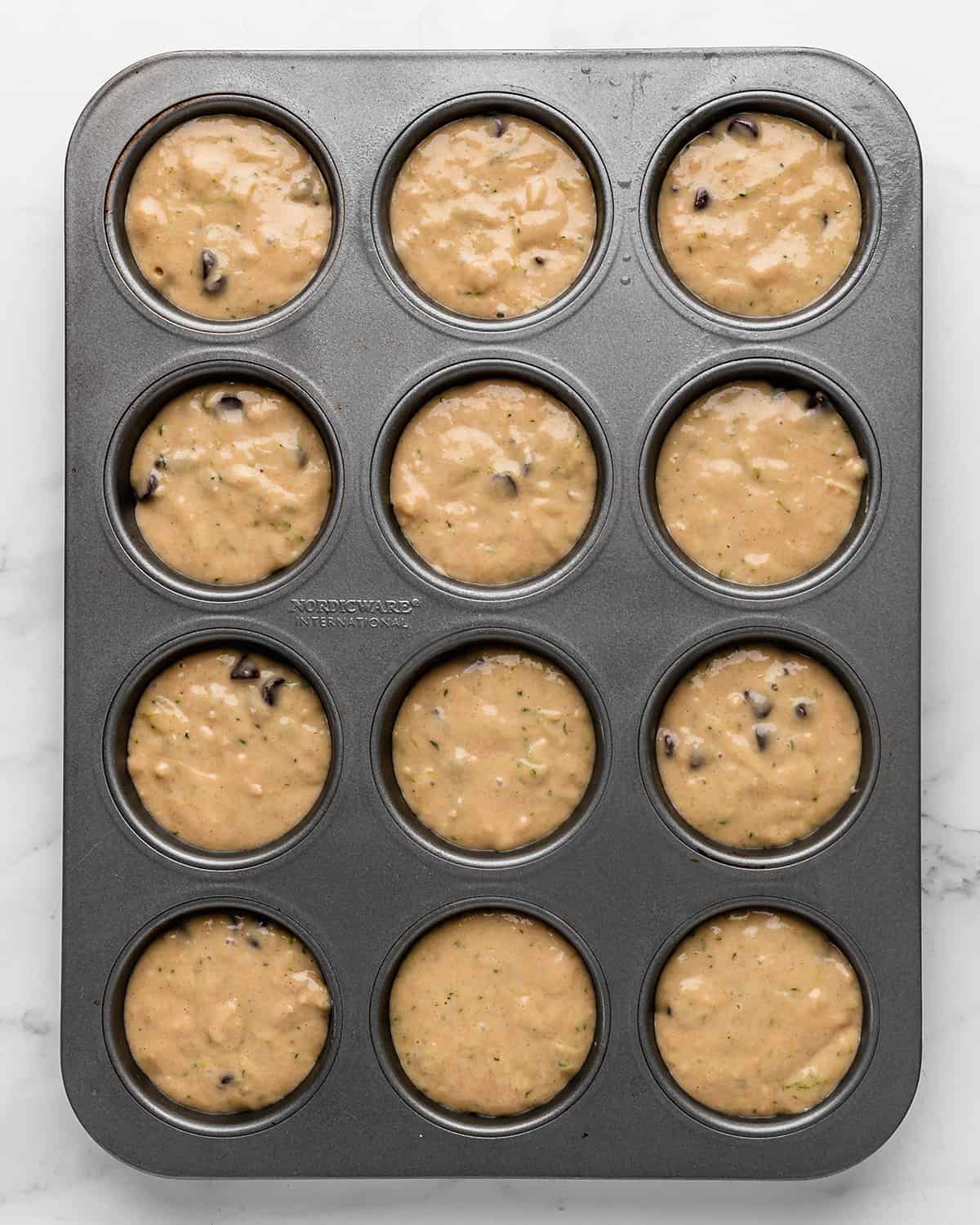 zucchini chocolate chip muffins in a muffin tin before baking