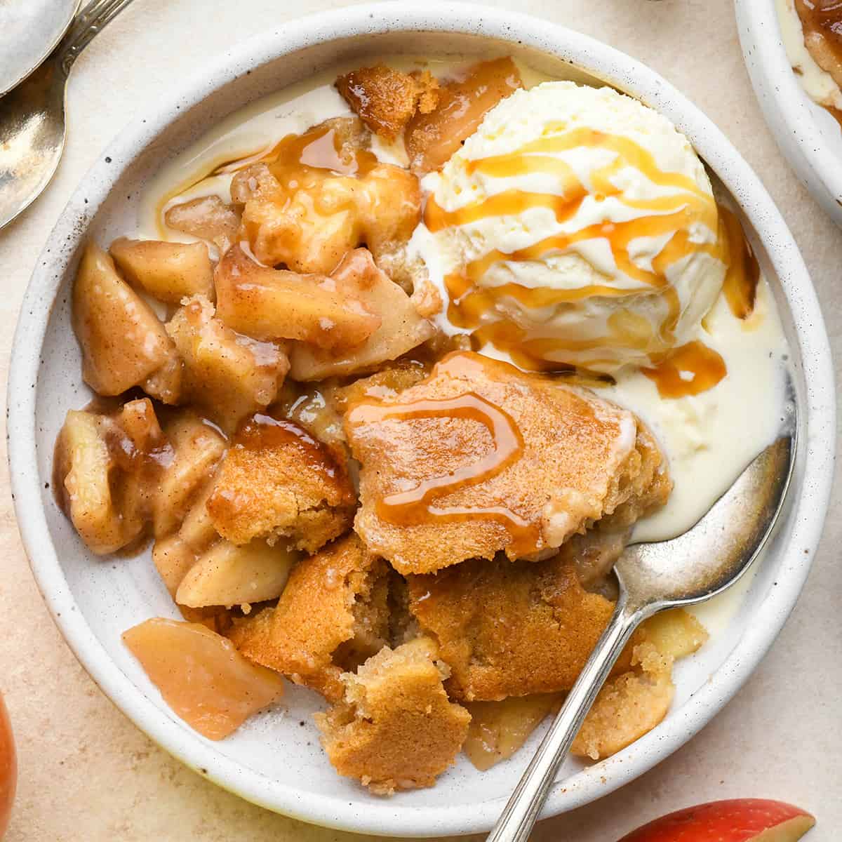 Apple Cobbler in a bowl with a spoon, vanilla ice cream and caramel sauce