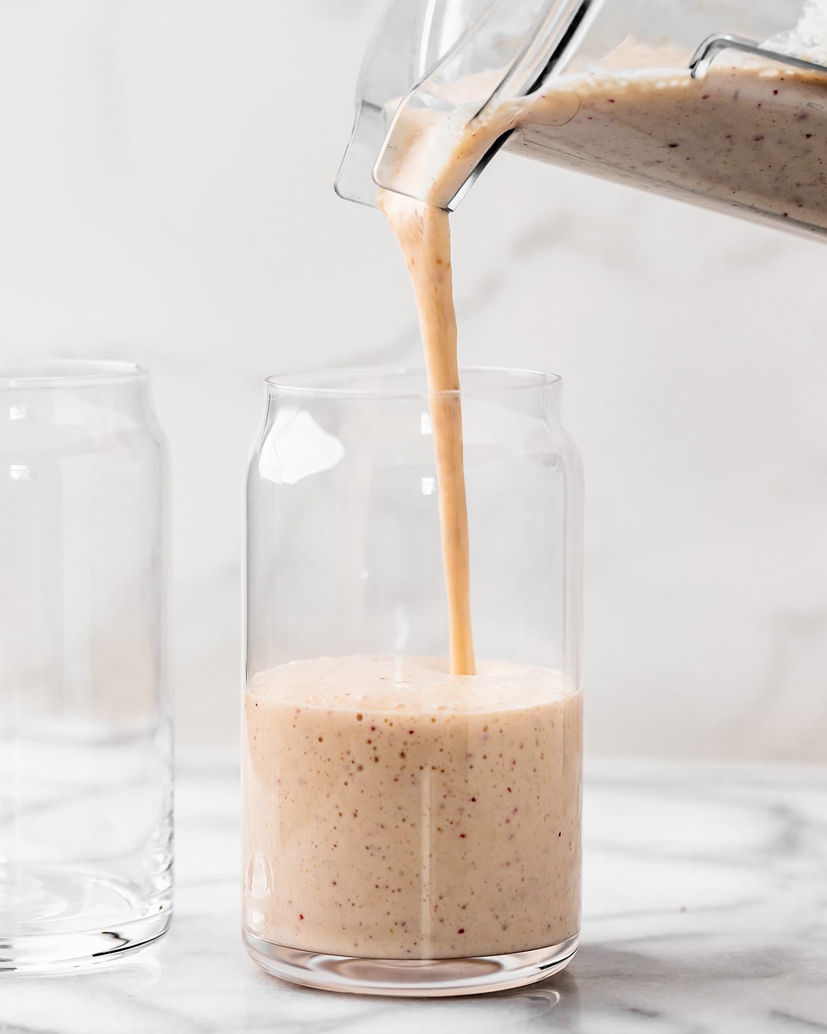 Apple Smoothie being poured into a glass from a blending container