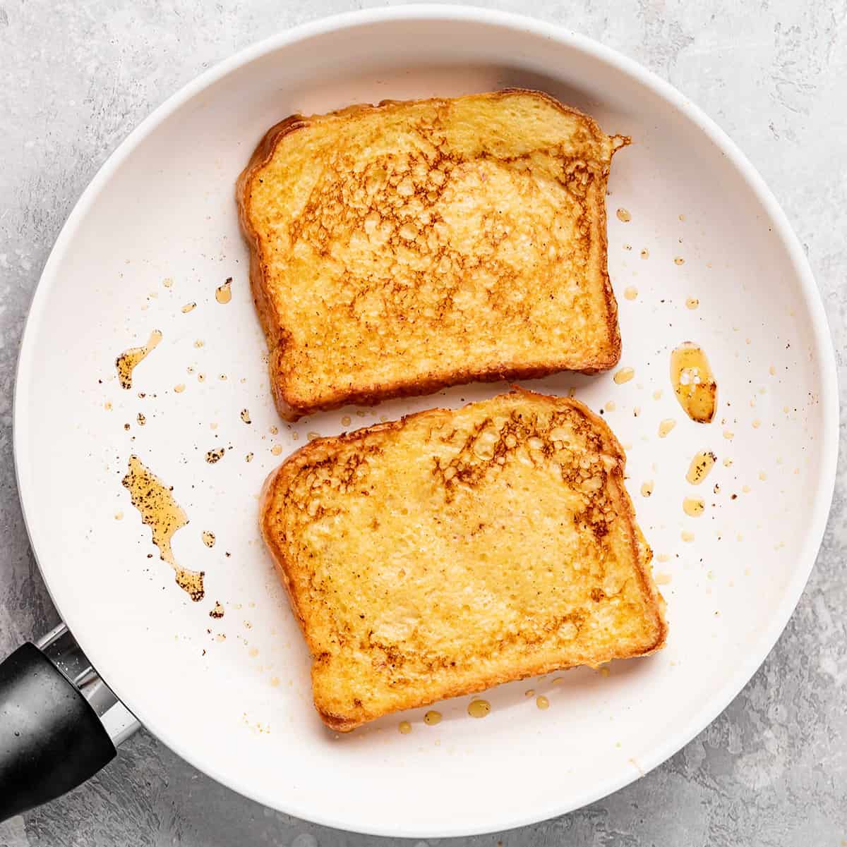 french toast in a frying pan being cooked on the second side
