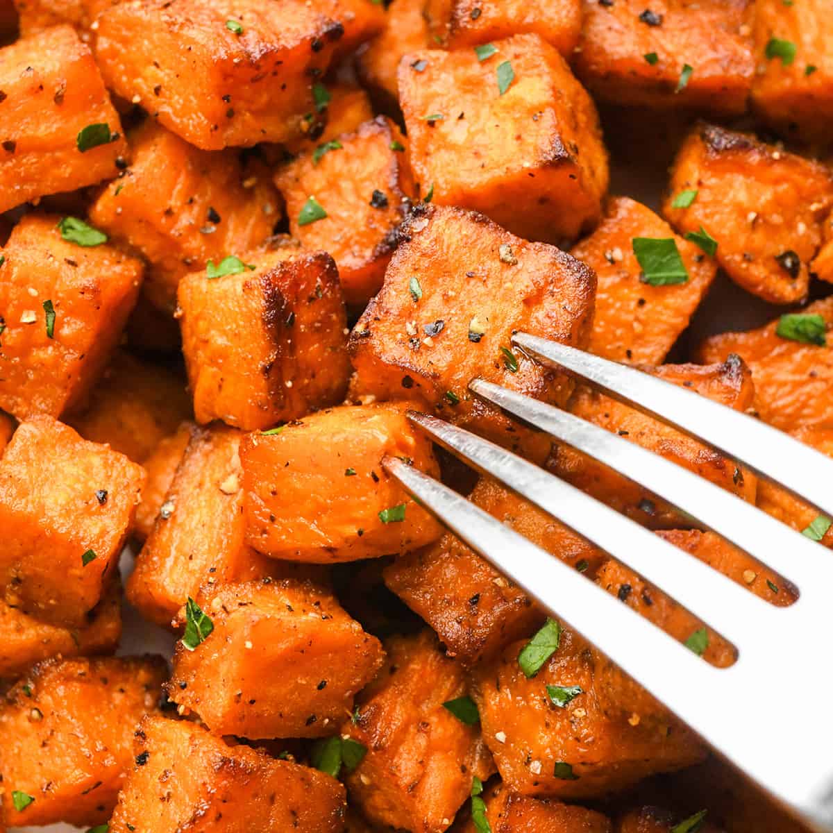 a fork taking a bite of  Oven Roasted Sweet Potatoes