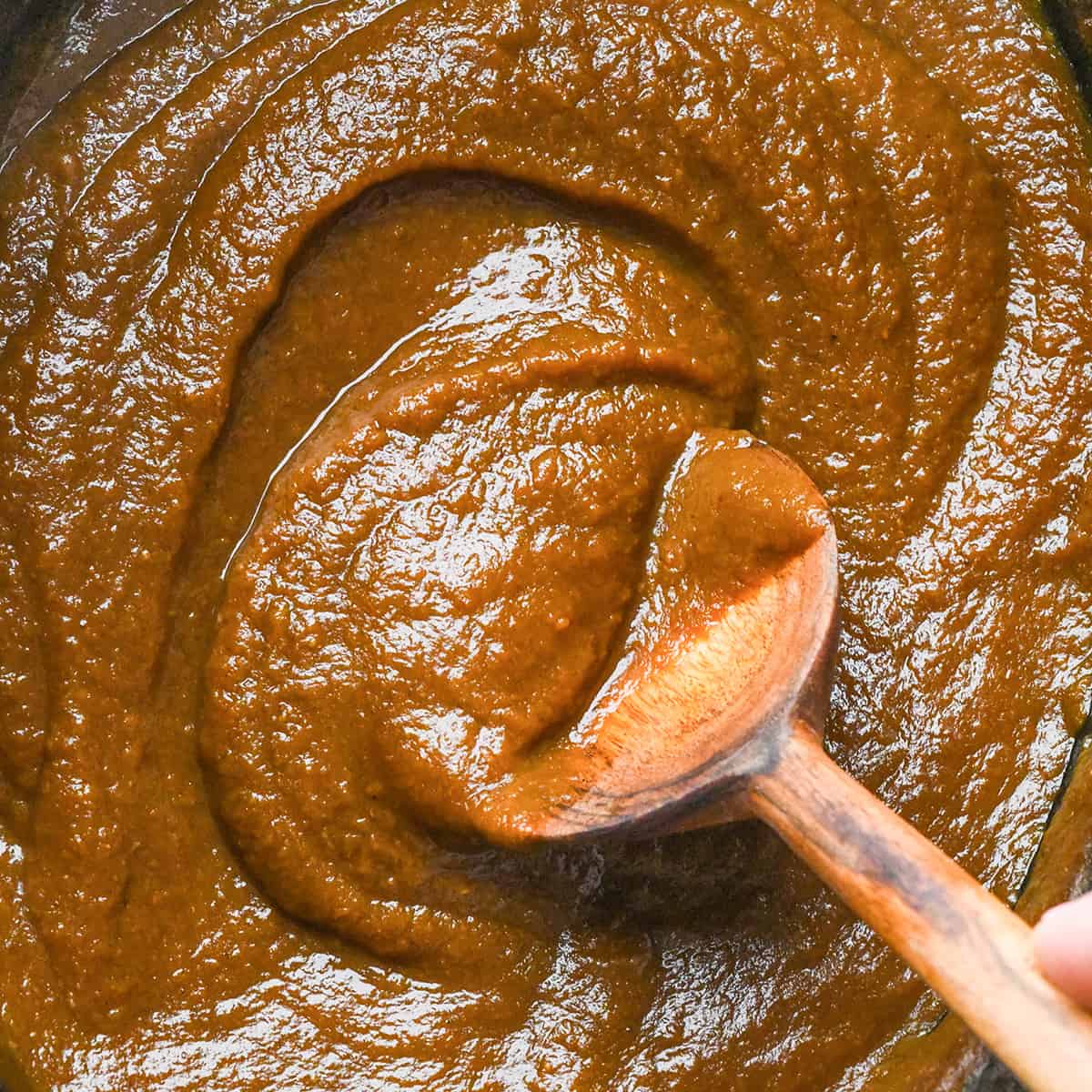 Pumpkin Butter in a crockpot with a wooden spoon