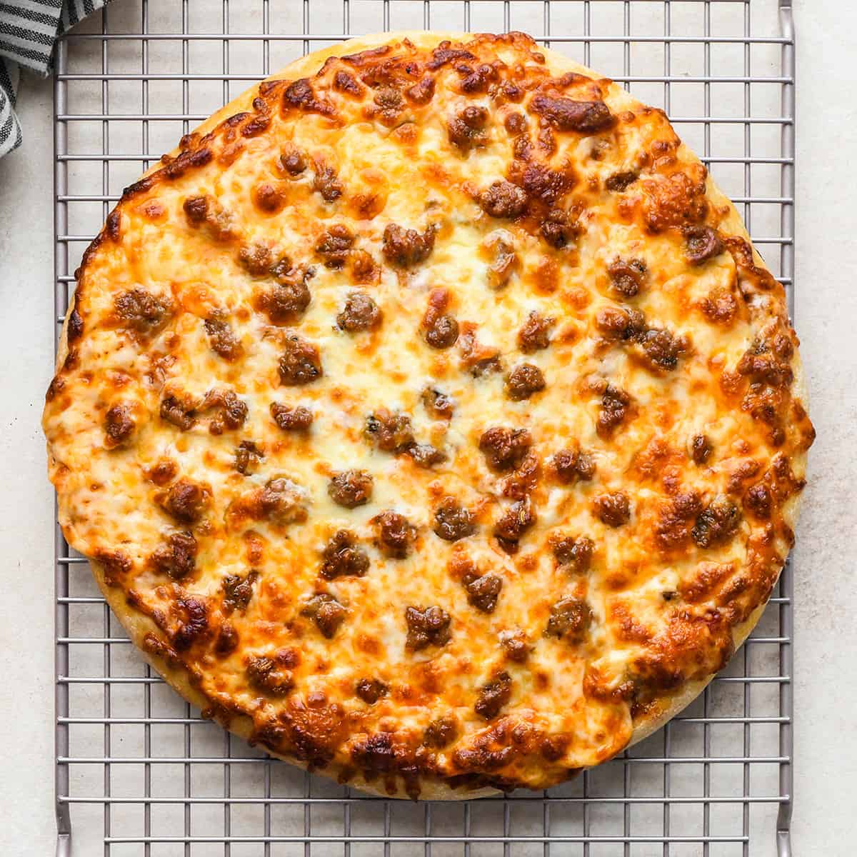 a round Sausage Pizza on a wire cooling rack